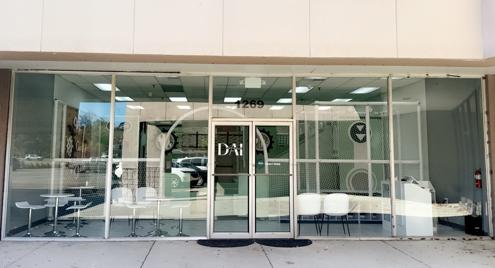 Glass storefront with two beds inside, reflections on glass, and a door in the center.