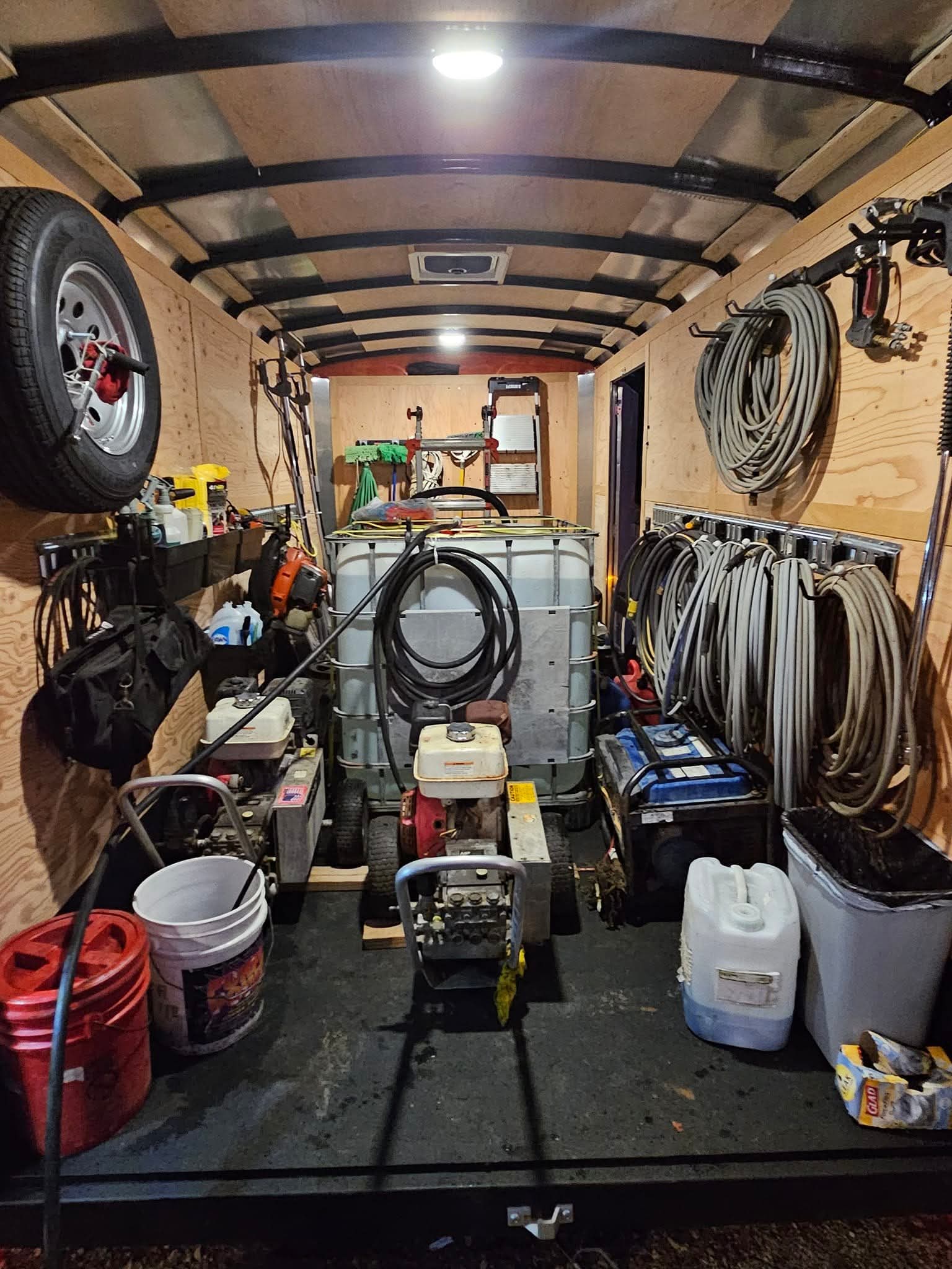 Inside a well-organized workshop with tools, hoses, and equipment stored on walls and shelves, viewed from the rear.