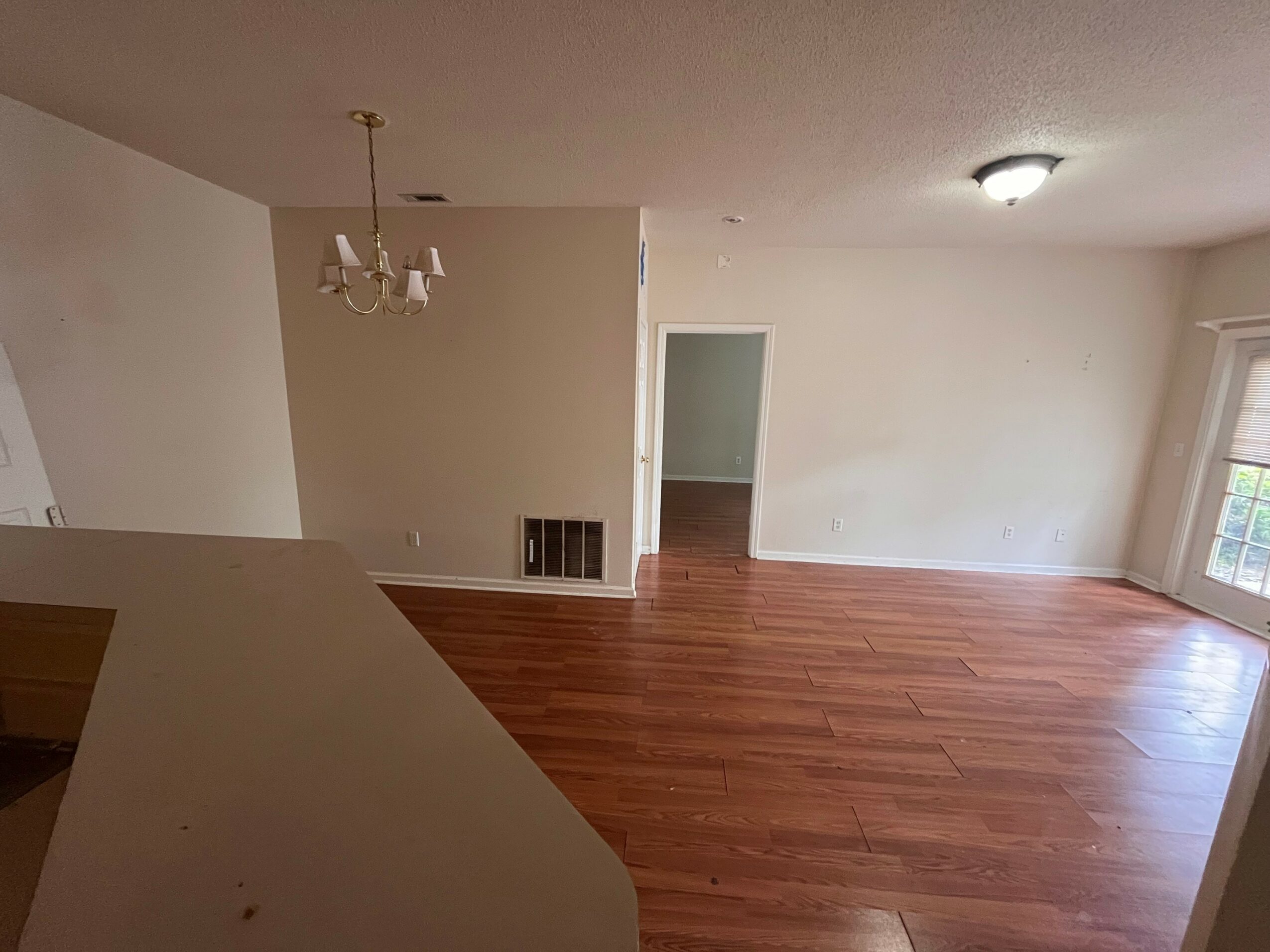 Empty room with hardwood floor, white walls, a window, and a ceiling light fixture.