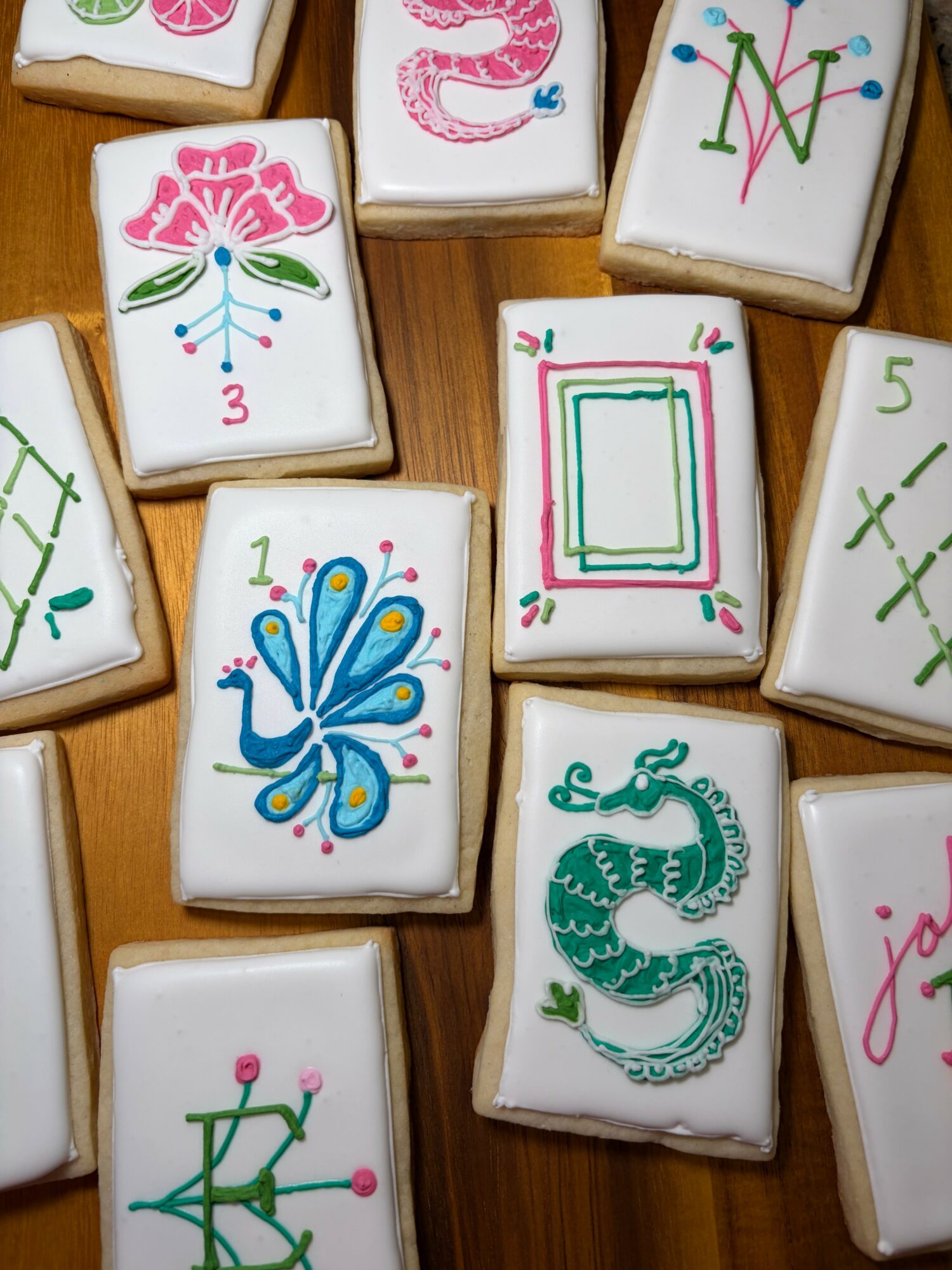 Decorated rectangular cookies with colorful floral, butterfly, and dragon designs on a wooden surface.