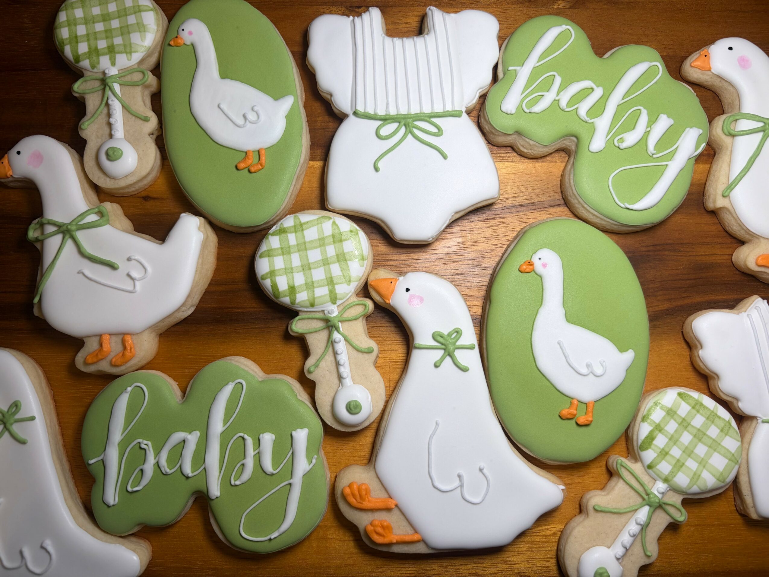 Decorative cookies with baby and duck themes, including ones with the word 'baby' and green and white patterns.