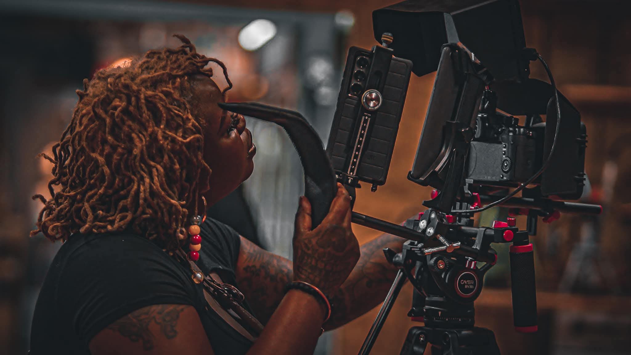 Person with curly hair operating a professional camera on a film set.