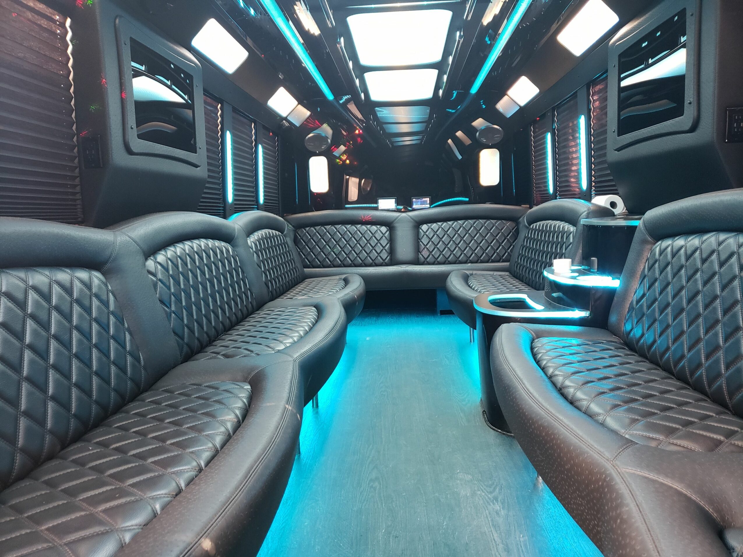 Interior of a futuristic lounge with quilted leather seats and blue LED lighting, arranged in a U-shape.