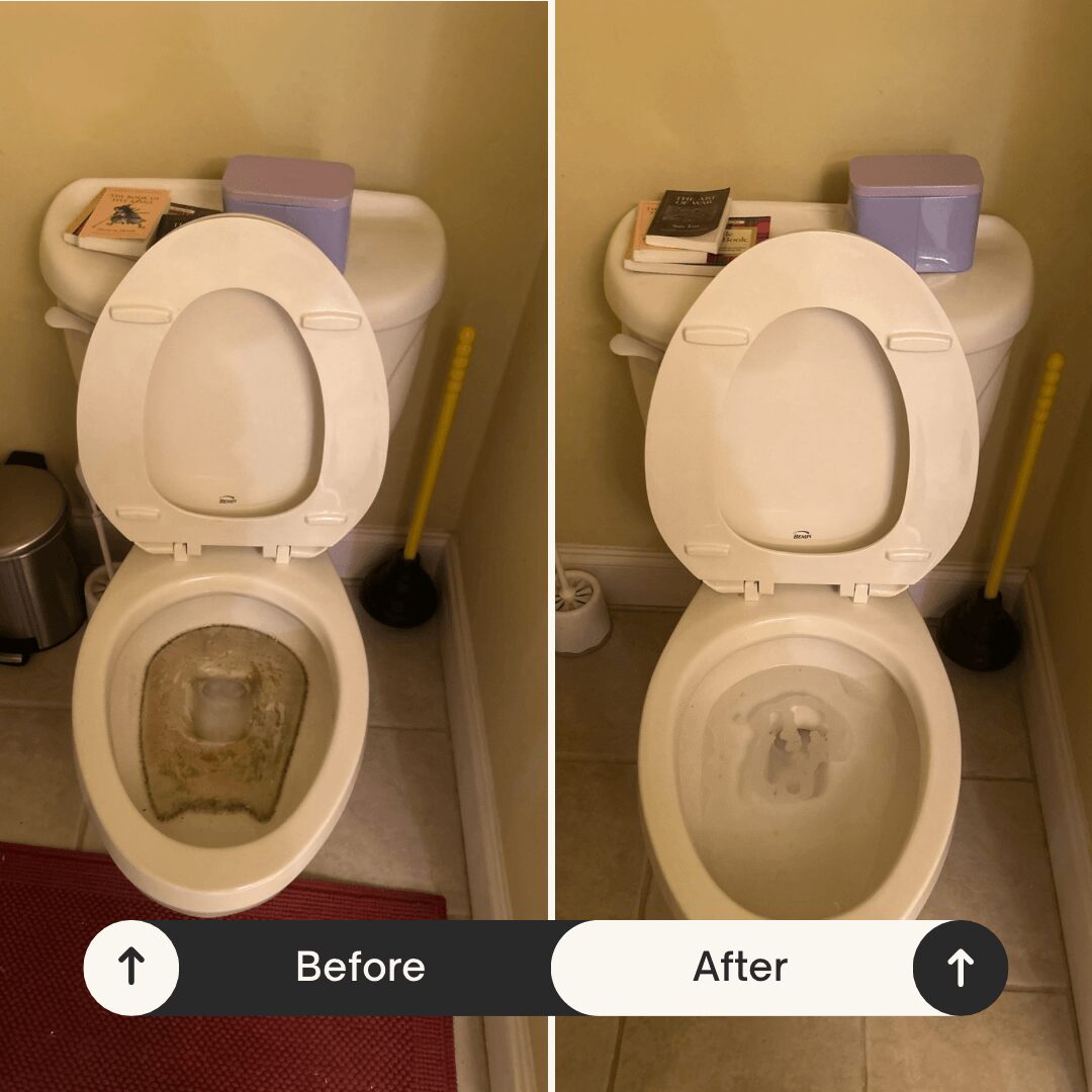 Toilet with open lid, cleaning supplies, and a yellow mop handle in a bathroom corner.