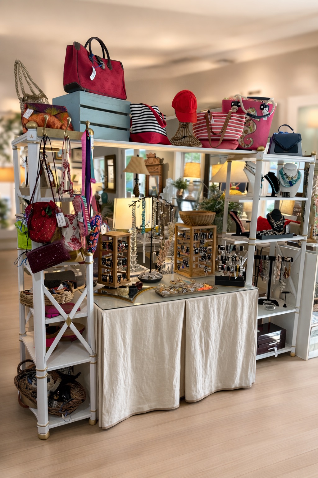Display of handbags, jewelry, and decorative items on shelves and table in a store.