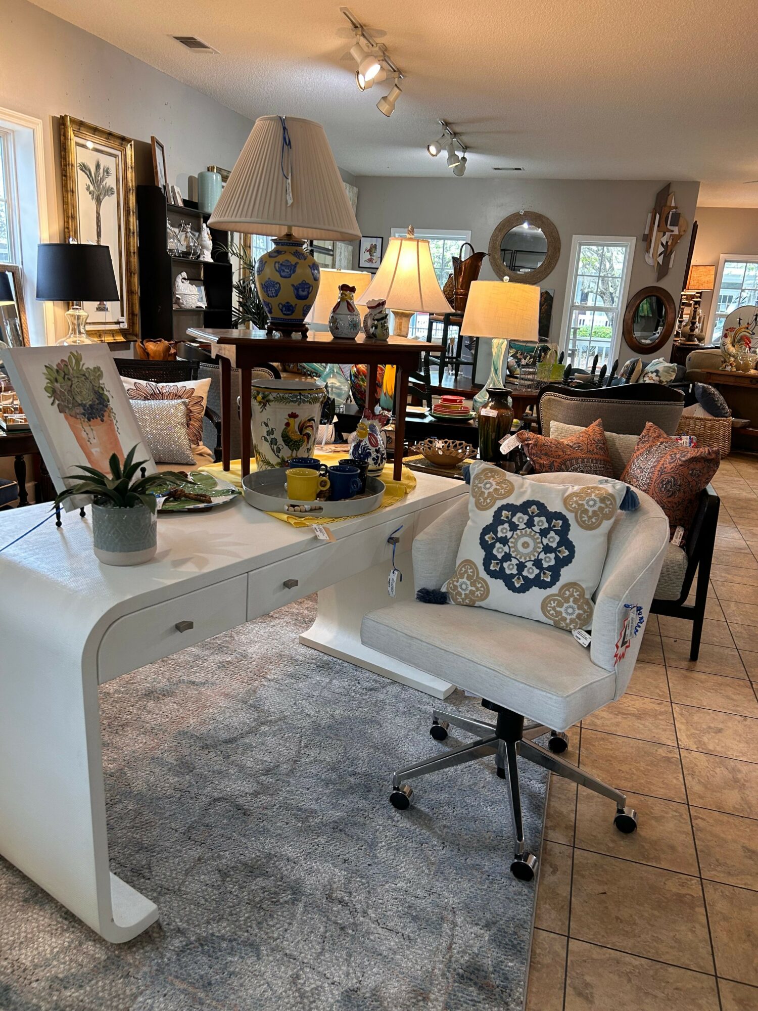 Office chair with a white cushion and blue floral pillow in a room with various lamps and furniture.
