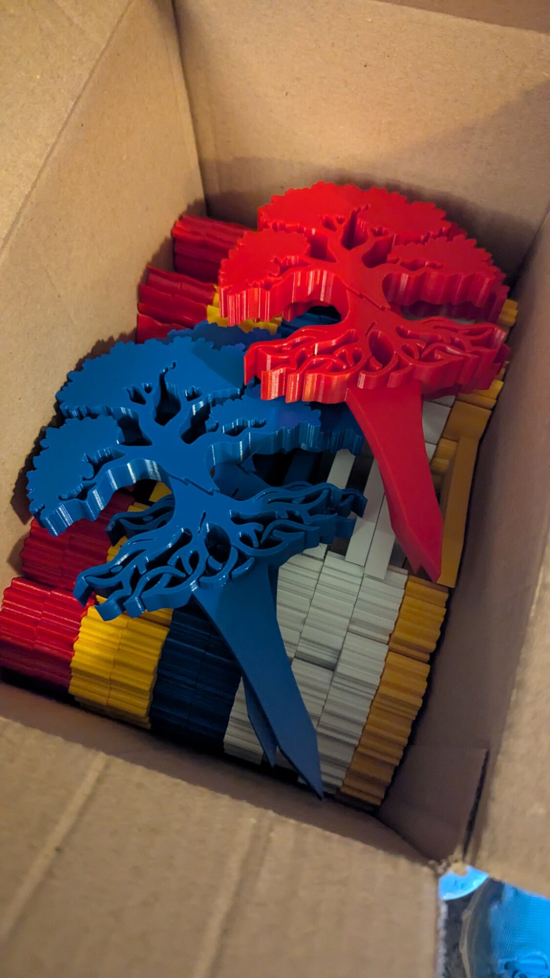 Box filled with colorful plastic cable organizers in red, blue, yellow, and black.