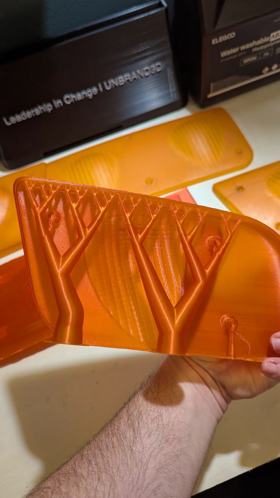 Person holding an orange plastic object with multiple compartments, with boxes in the background.