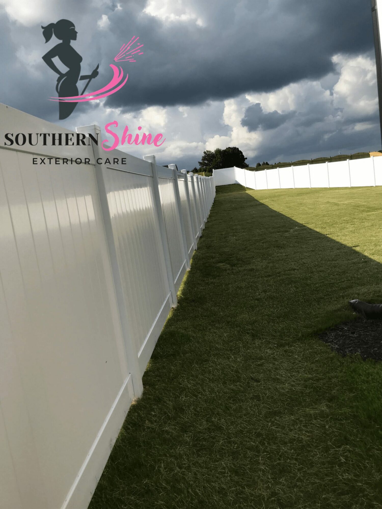 White fence runs along a grassy area under a cloudy sky, with a logo and text in the upper left corner.