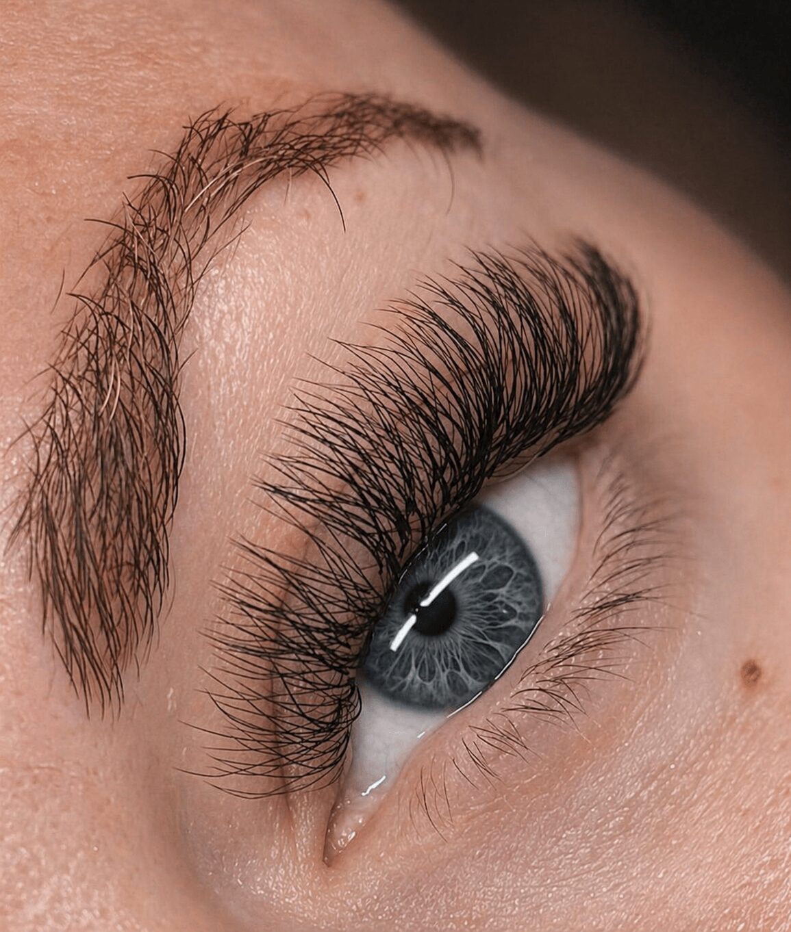 Close-up of a person's eye with long, thick eyelashes and blue iris.