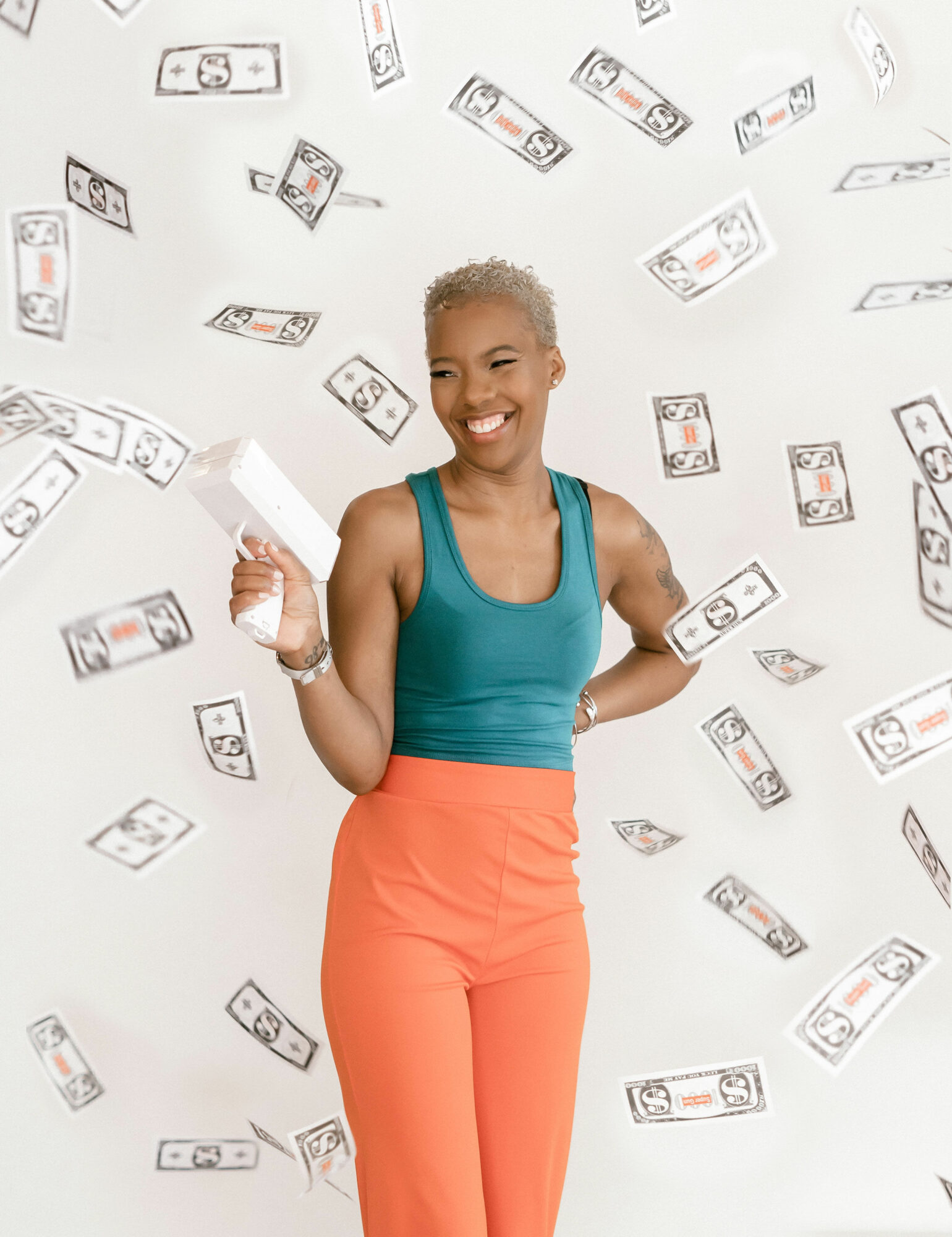 Woman smiling, holding a white box, surrounded by falling dollar bills, wearing a teal top and orange pants.