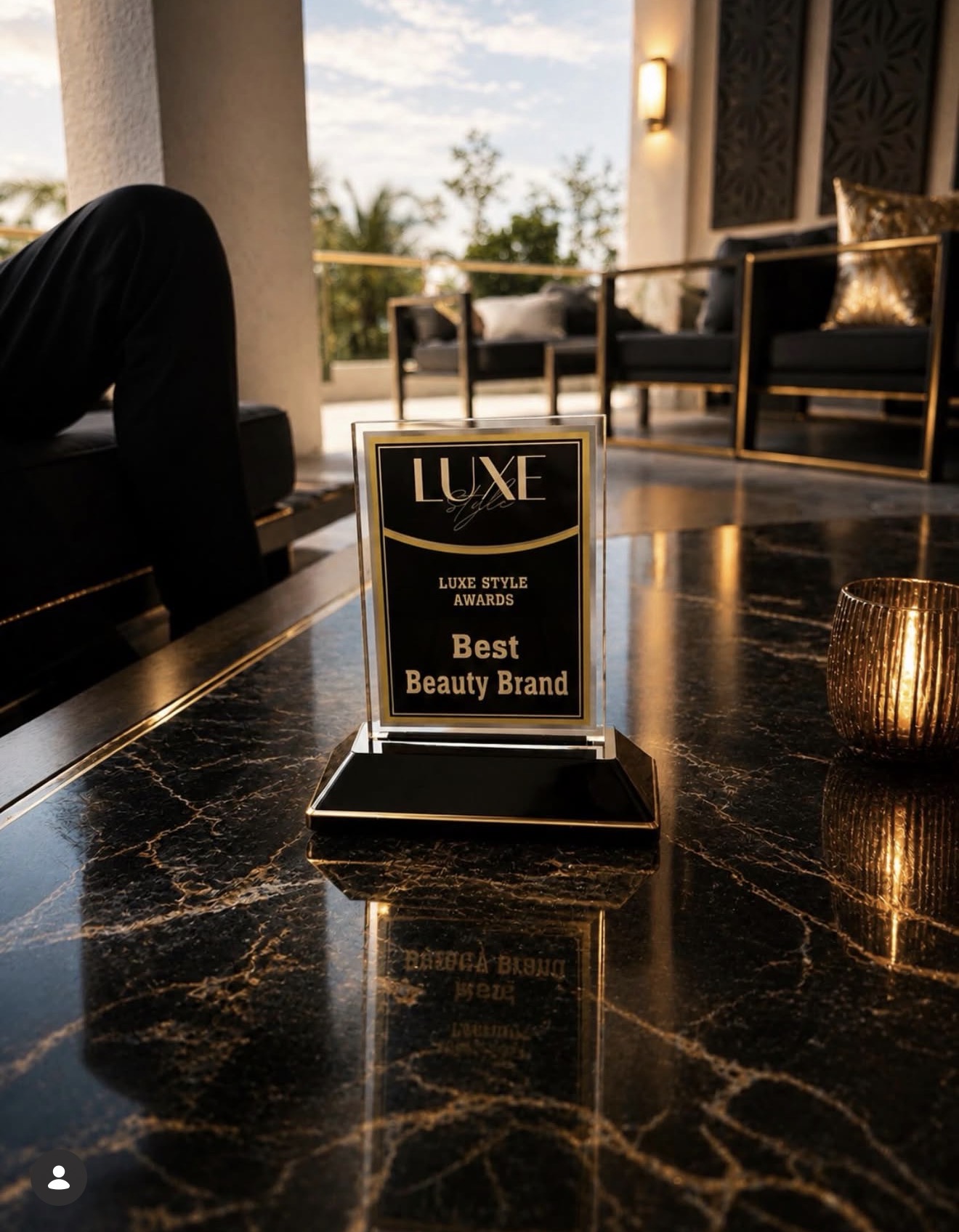 Award plaque on a marble table with a blurred background of a luxurious room and outdoor view, gold accents visible.