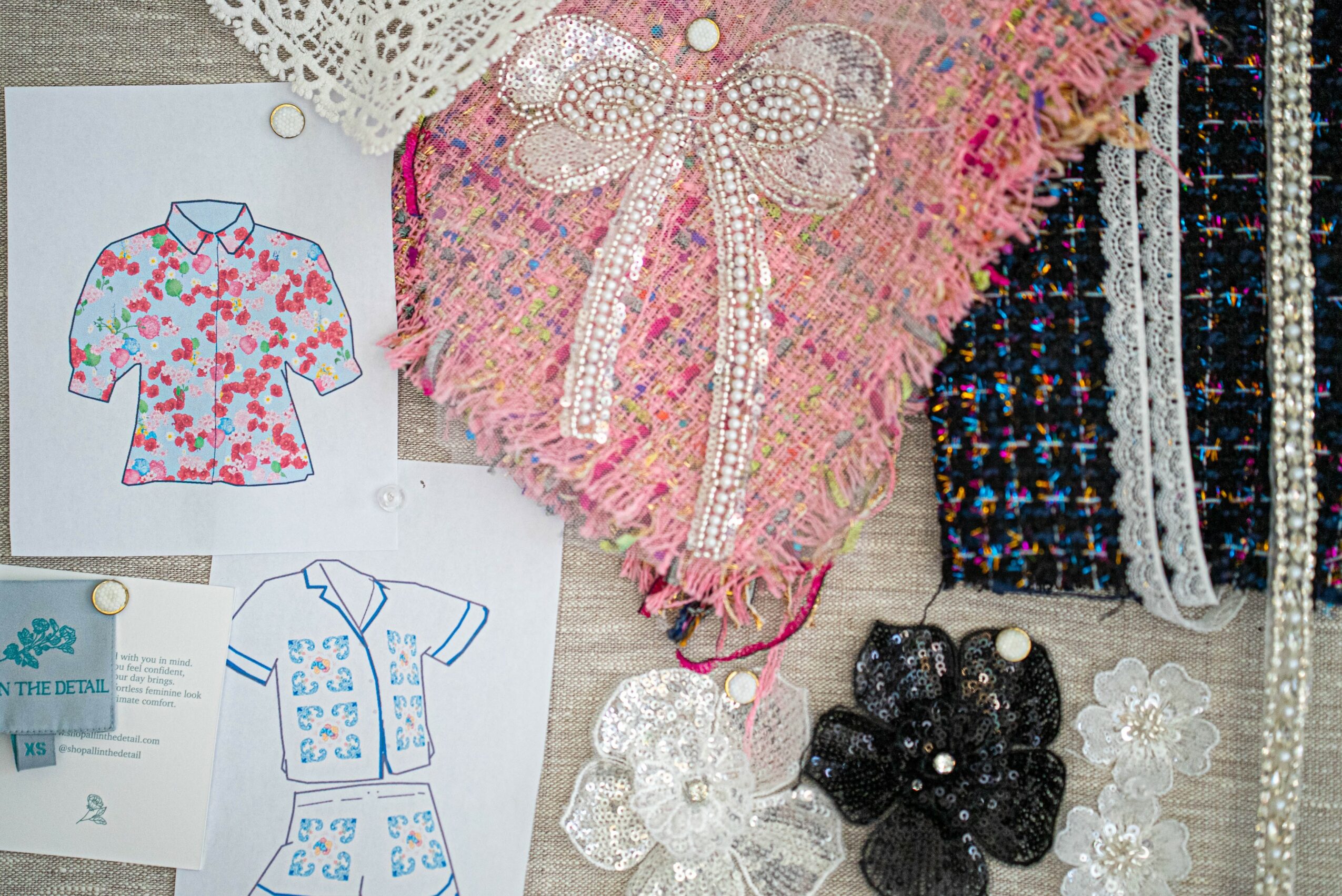 Various fabric swatches and paper sketches of clothing designs, including a floral shirt pattern and textured textiles, on a surface.