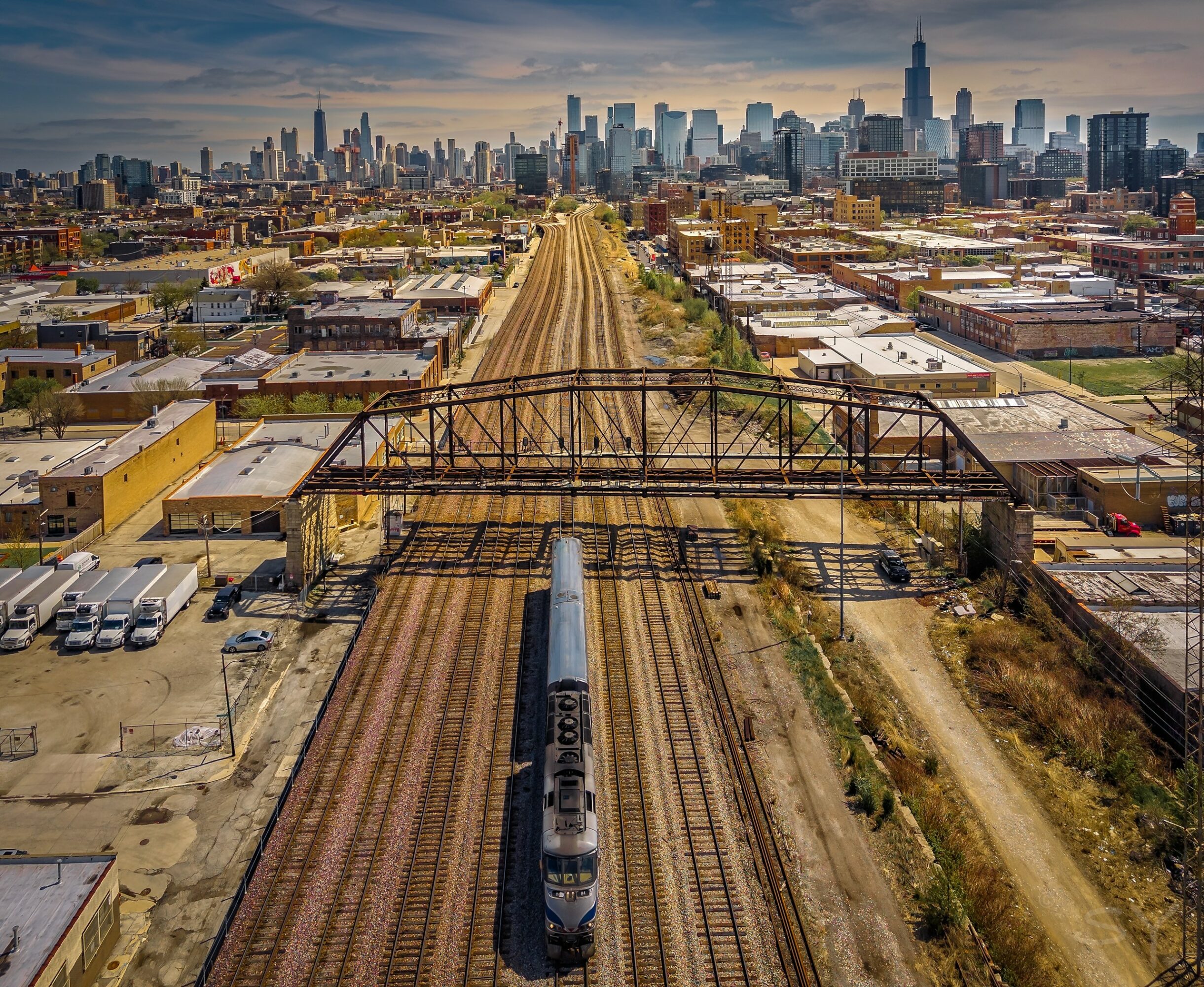 Train on tracks with city skyline in the background, clear sky, and urban landscape.