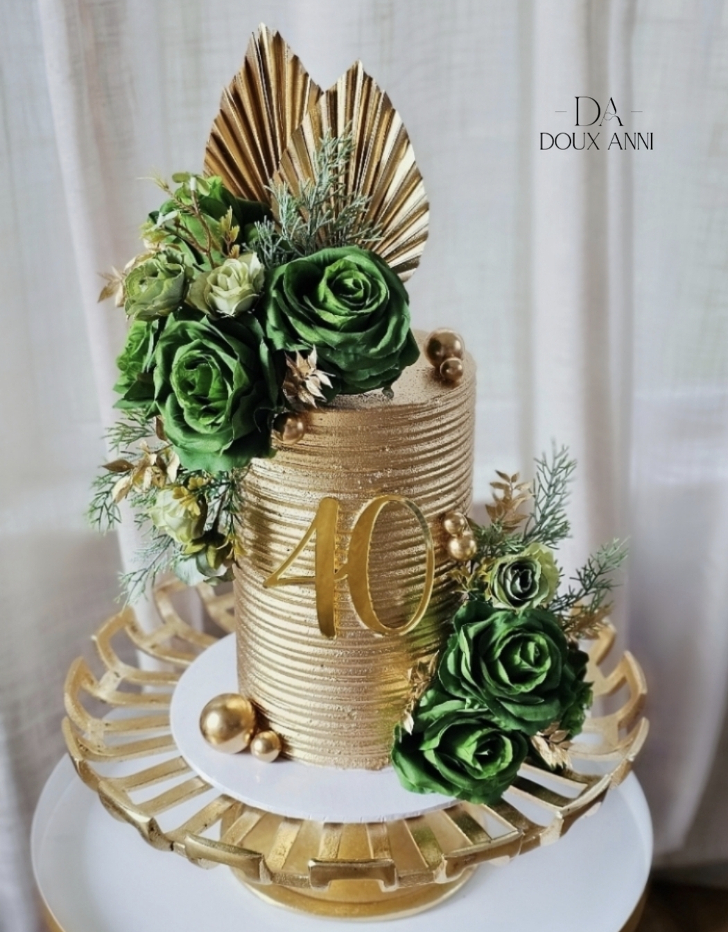 Decorative cake with green roses, gold accents, and a large gold number 40, on a gold tray with a white base.
