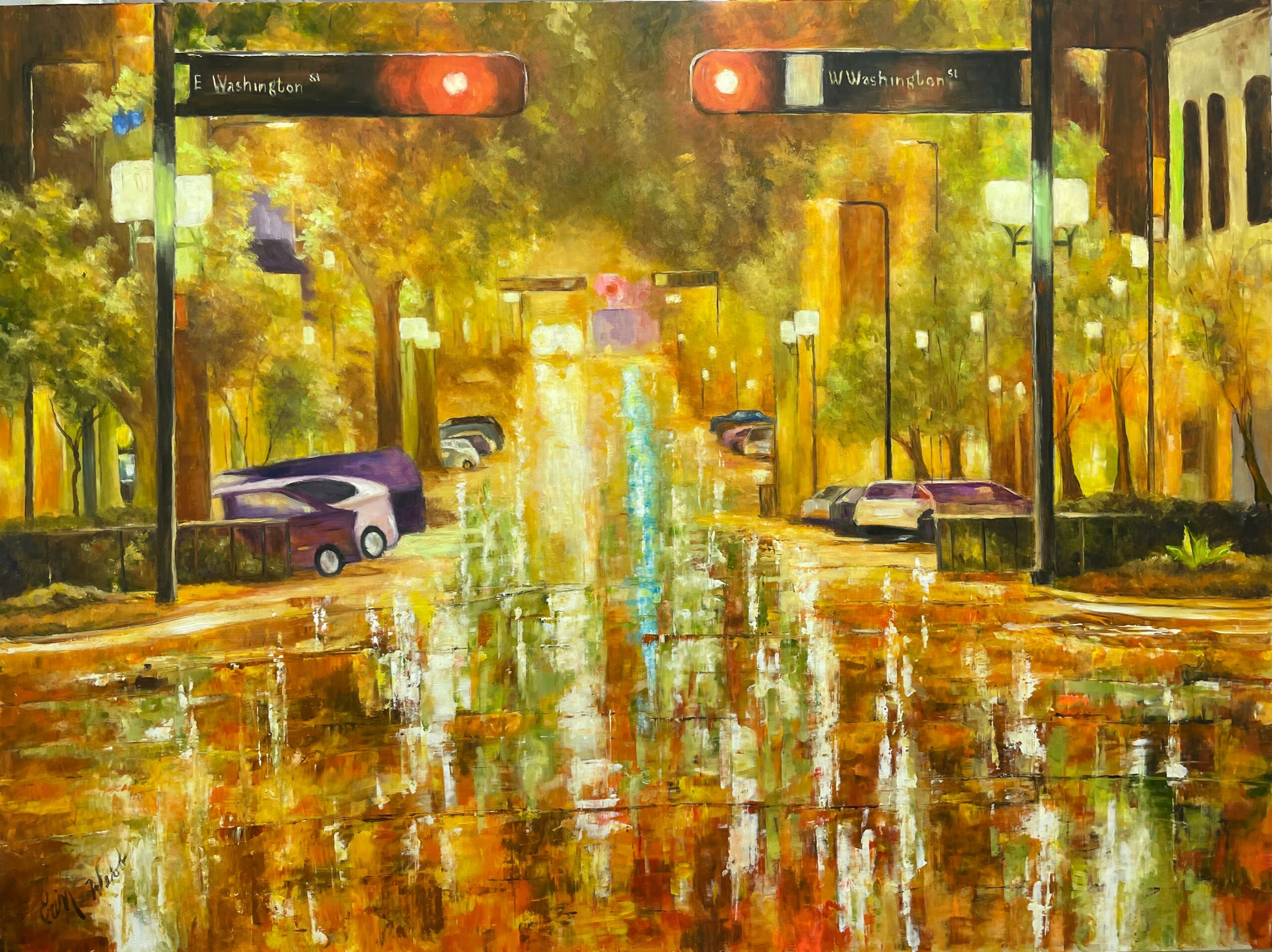 City street scene with traffic lights, parked cars, and trees reflected in wet pavement, during daytime with autumn colors.