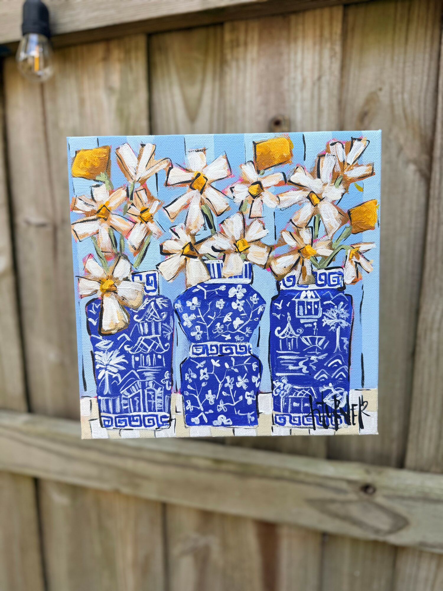 Painting of white flowers with yellow centers in three blue vases against a light background, on a wooden fence.