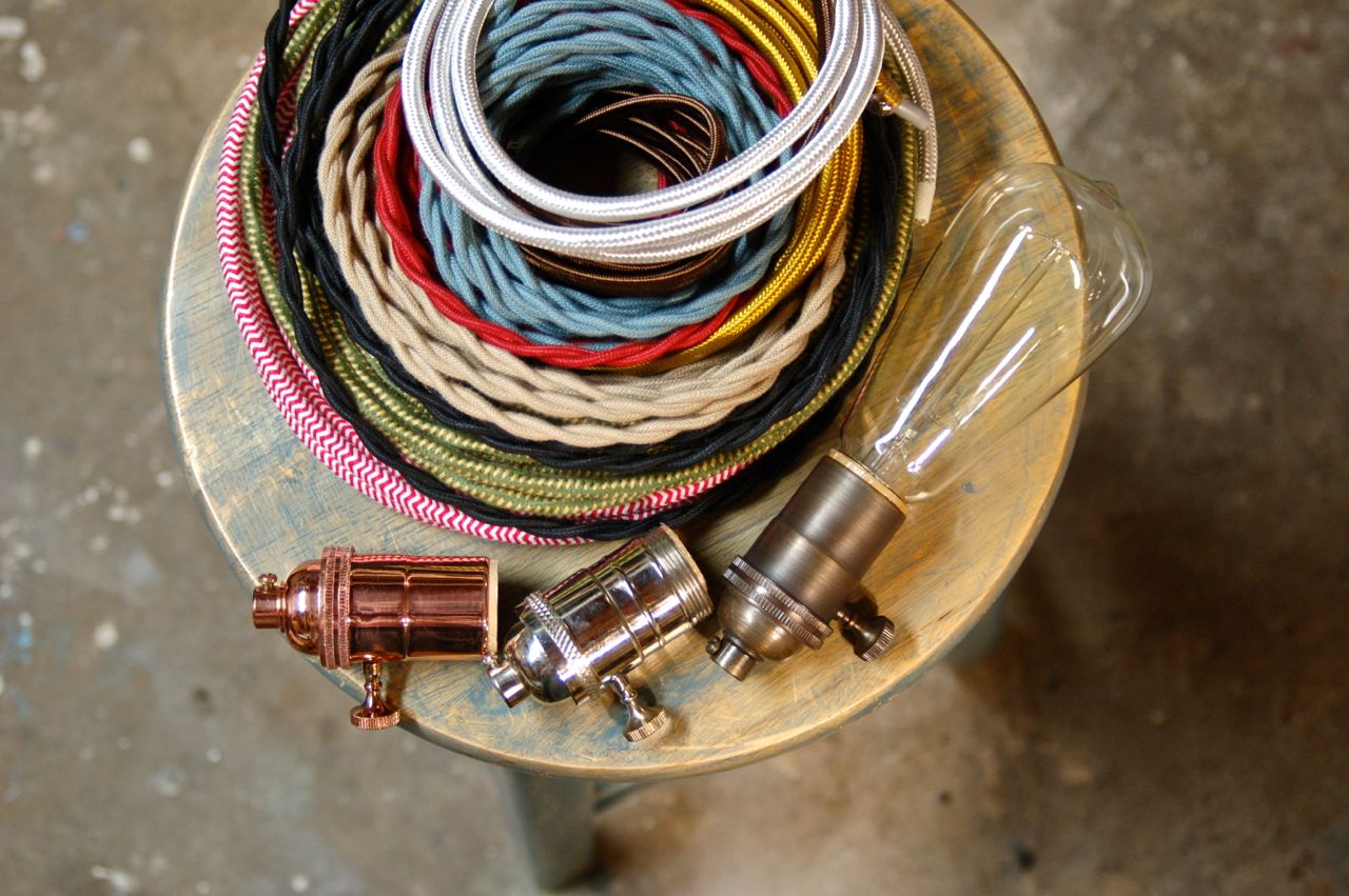 Coiled colorful cords and metallic light bulbs on a glass surface, viewed from above.