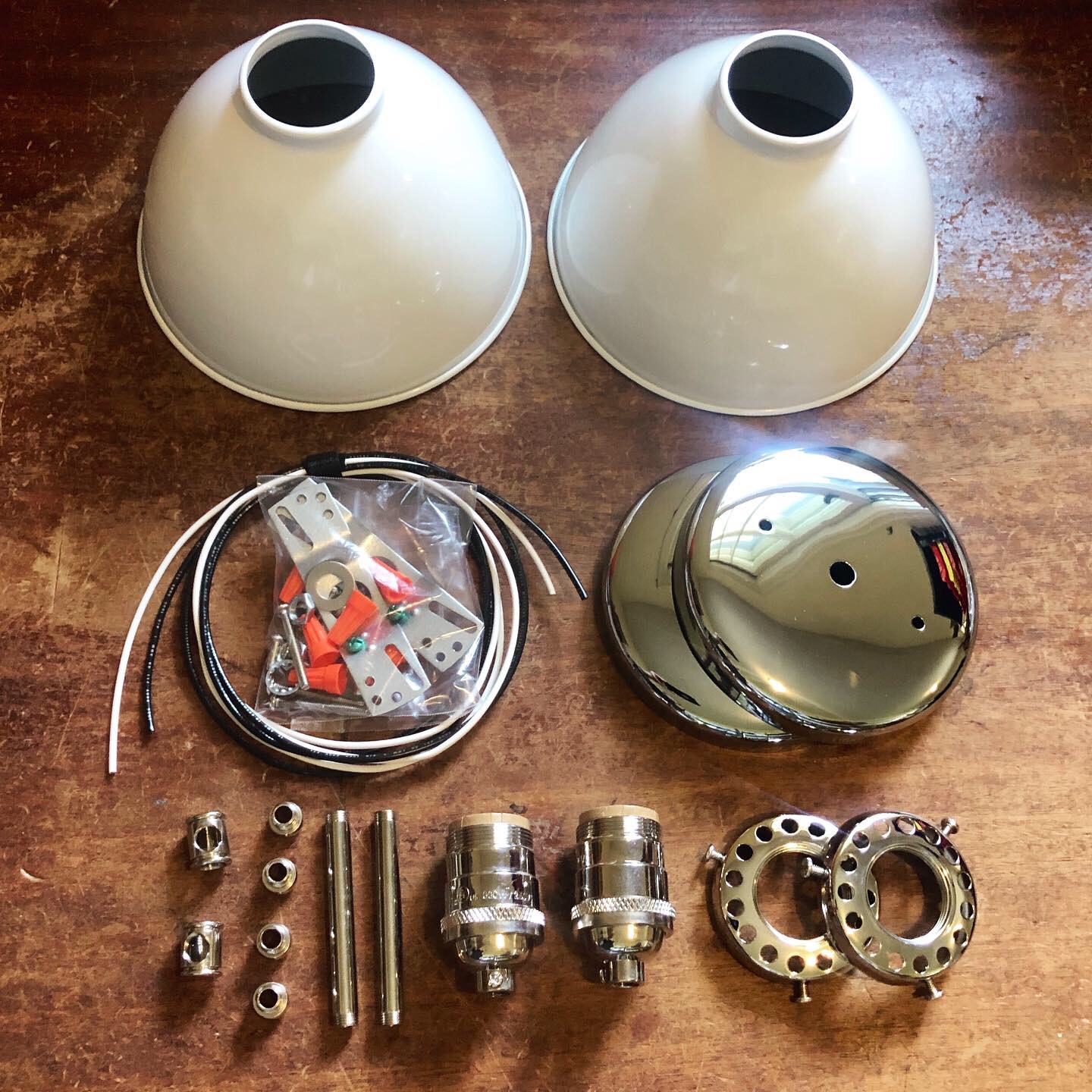 Two white dome-shaped objects, two metal cylindrical parts, and various small metal components on a wooden surface.