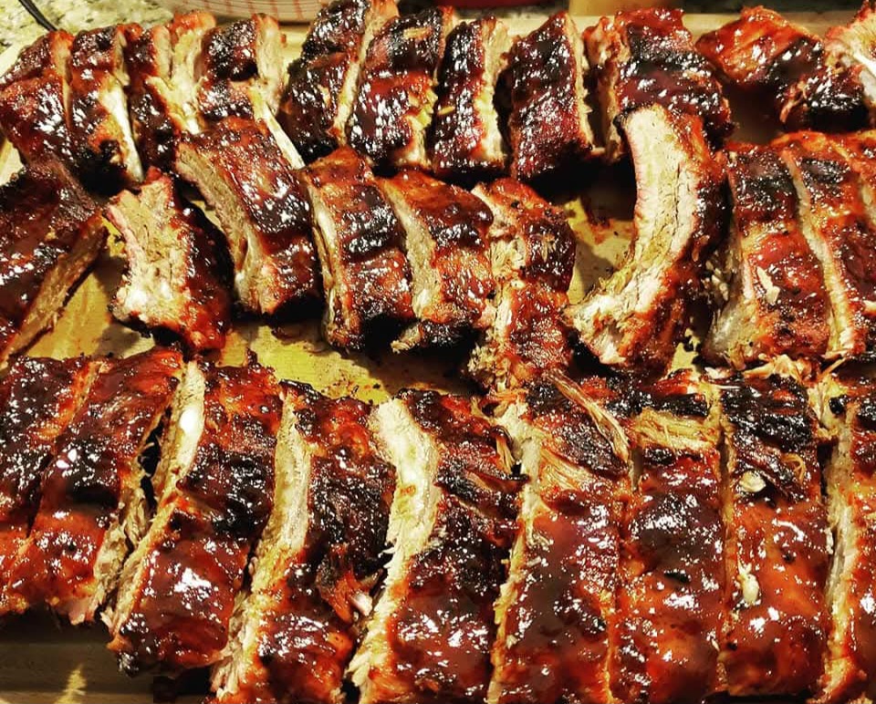 Barbecue ribs arranged on a tray, glazed with sauce, with a shiny, caramelized appearance.