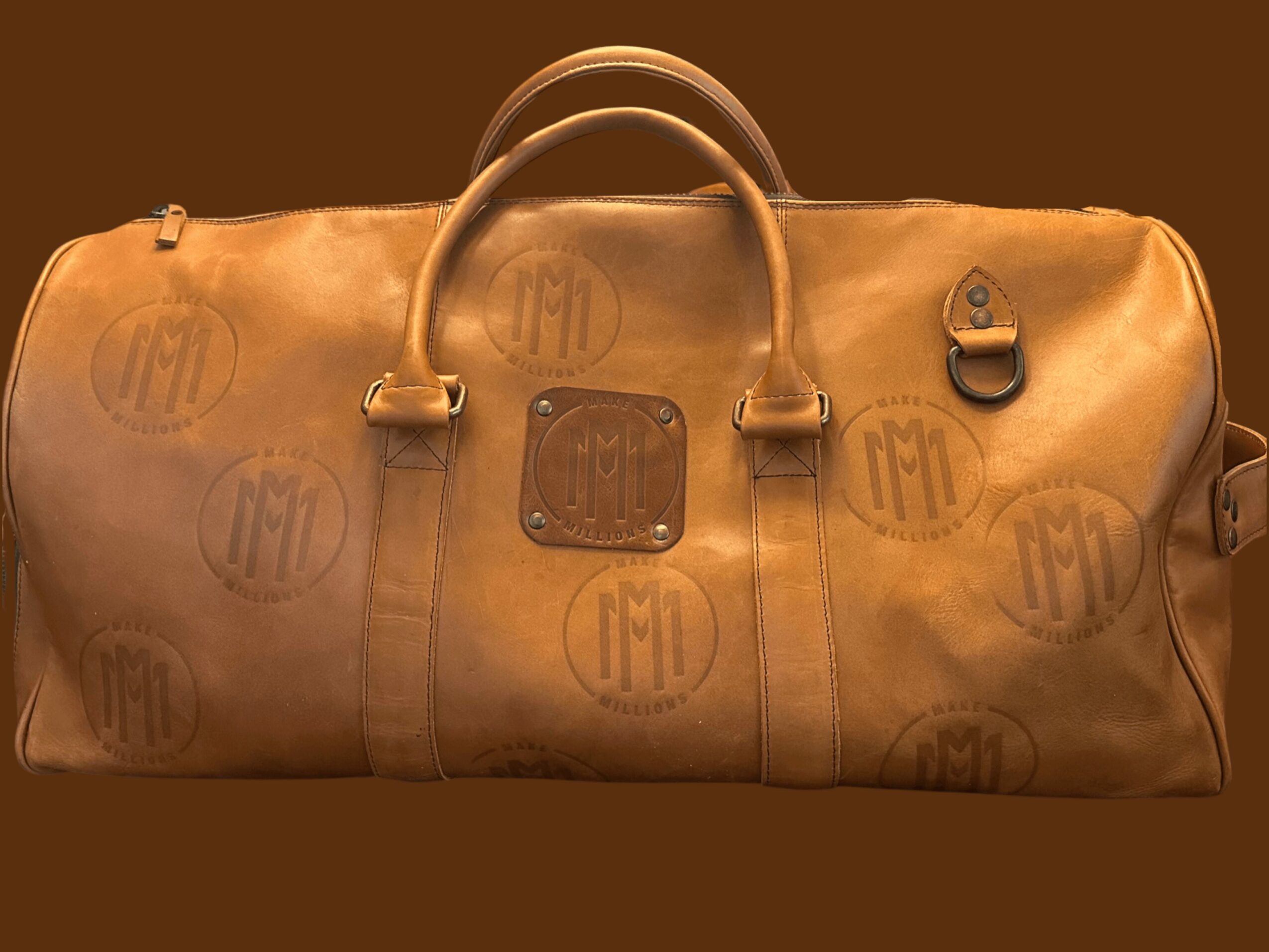 Leather duffel bag with handles and a lock, monogrammed with initials, on a brown background.