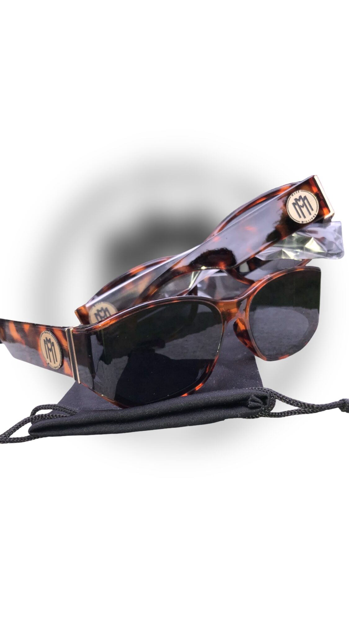 Pair of sunglasses with tortoiseshell frames and dark lenses, placed on a black case, with a blurred background.