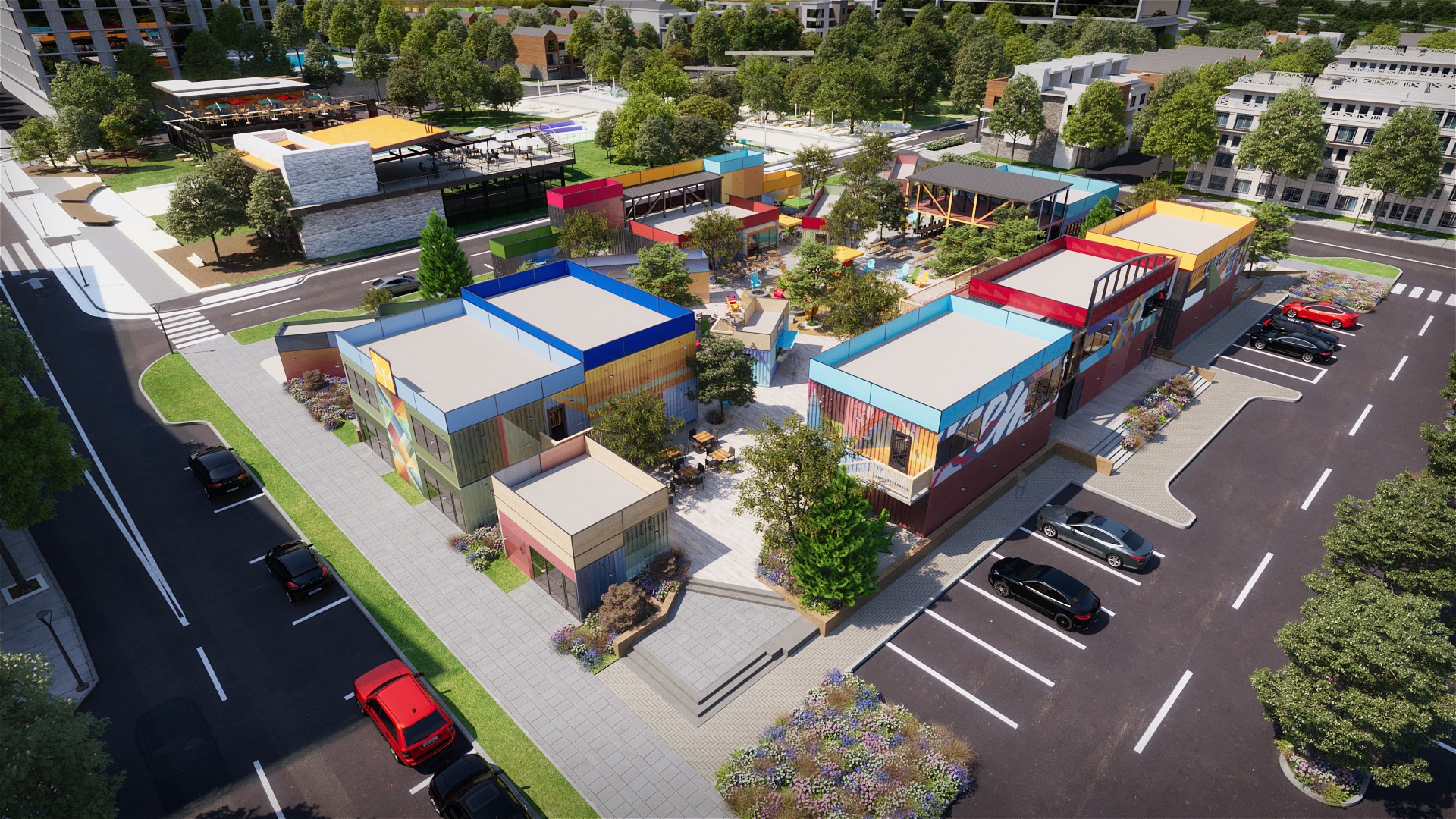 A colorful outdoor area with buildings, trees, and parking spaces, viewed from above in bright daylight.