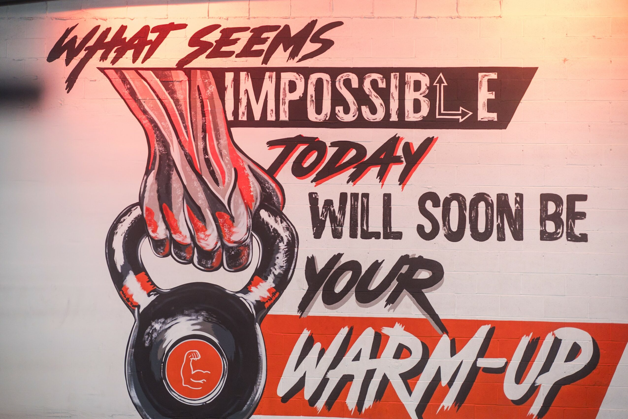 Graffiti with motivational quote and a hand gripping a kettlebell, in red, black, and white colors.