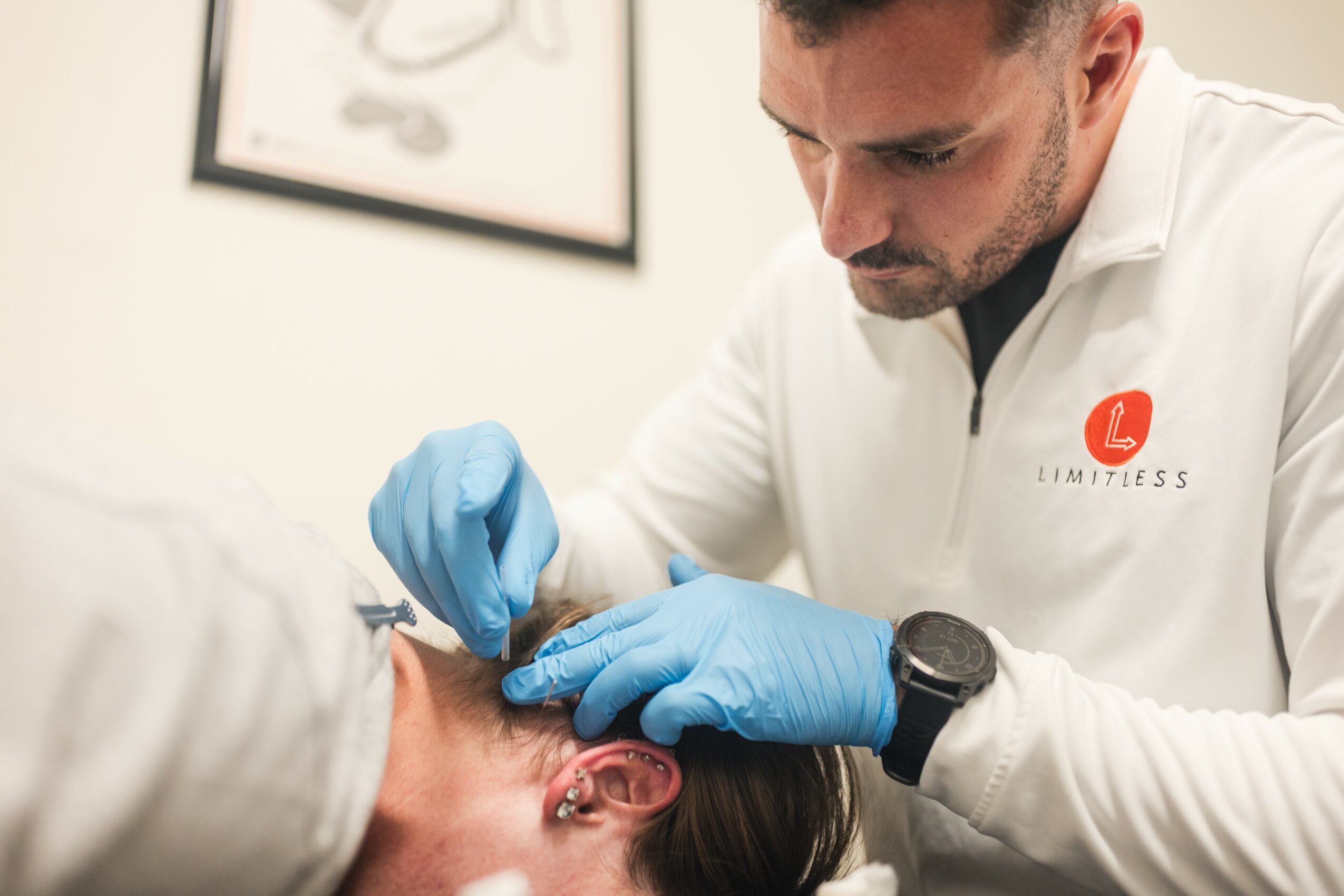 Medical professional in gloves administering an injection to a person's arm in a clinical setting.