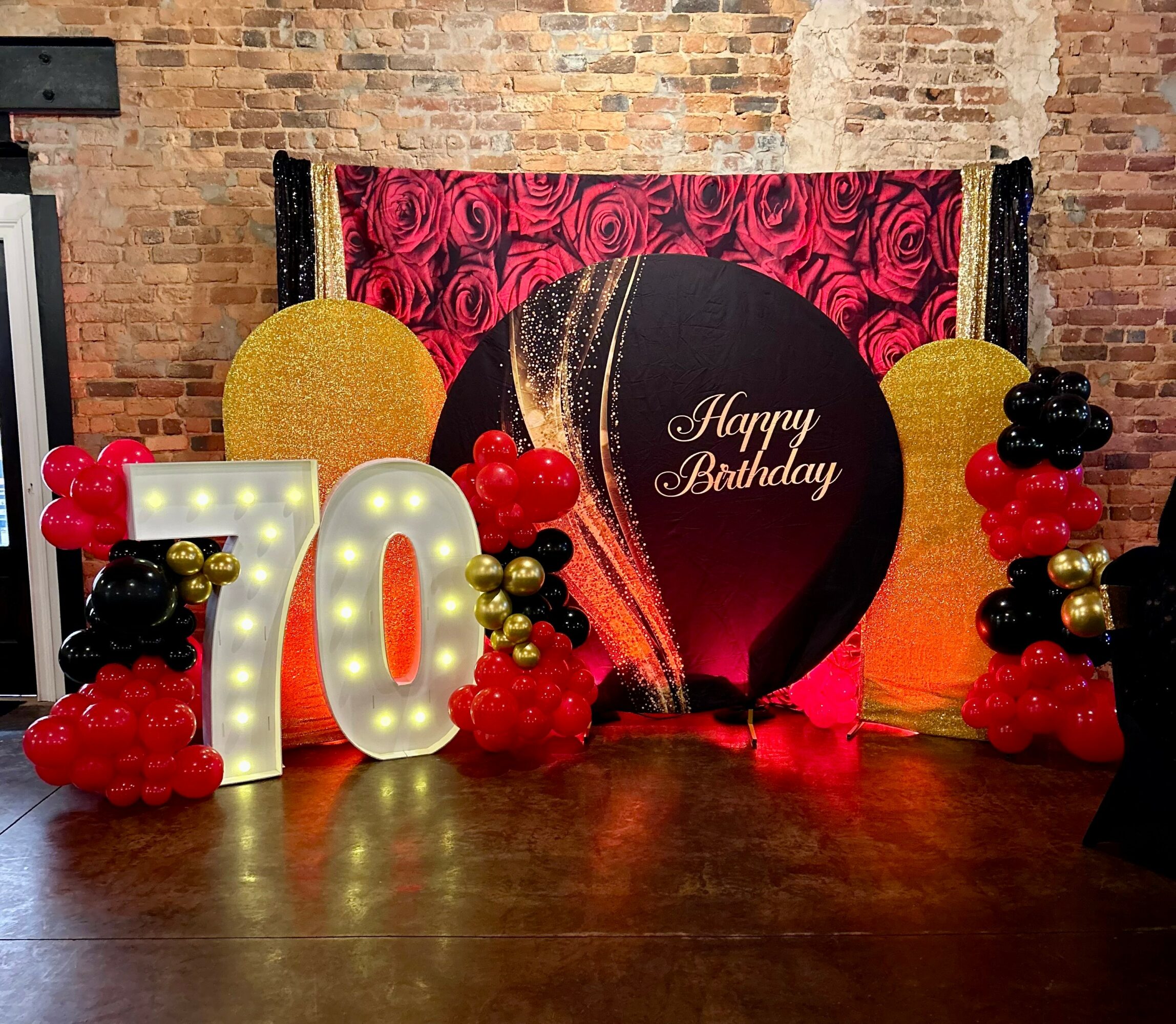 Decorative birthday setup with large illuminated number 10, balloons, and a backdrop with a birthday message.