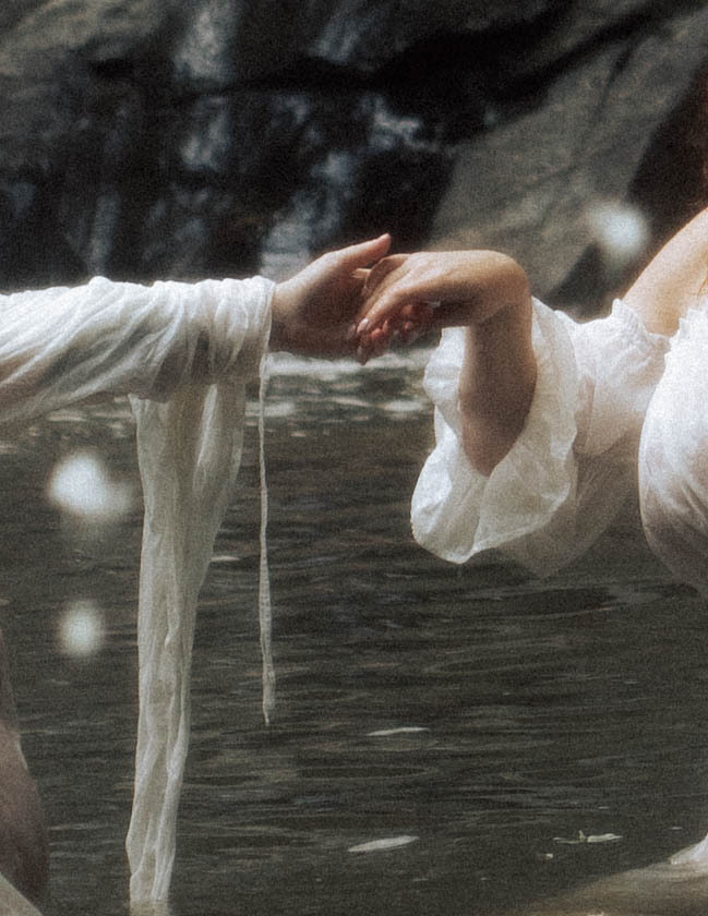 Two people holding hands above water, with one person's arm extended and the other person's hand gently grasping.