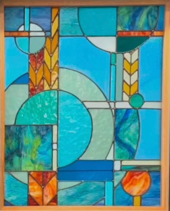 Colorful stained glass window with geometric shapes and patterns in blue, green, yellow, and orange hues.