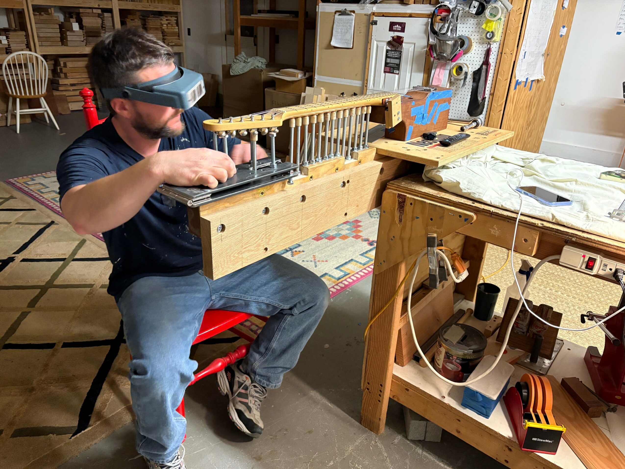 Child wearing safety goggles working with a woodworking tool on a workbench in a workshop.