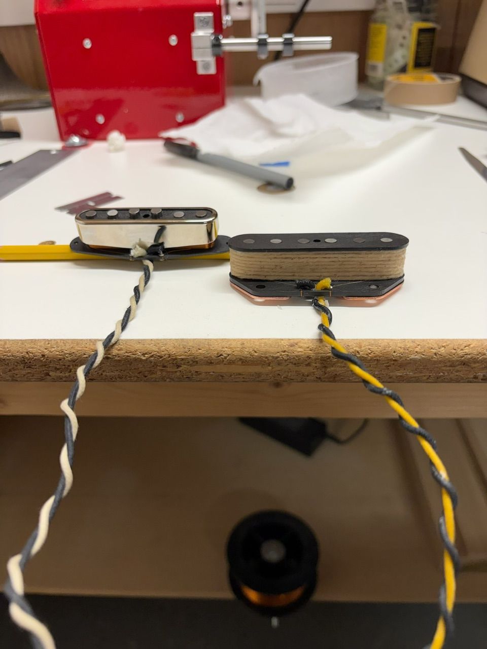 Two small black and orange electronic components connected by twisted yellow and black wires on a white surface.
