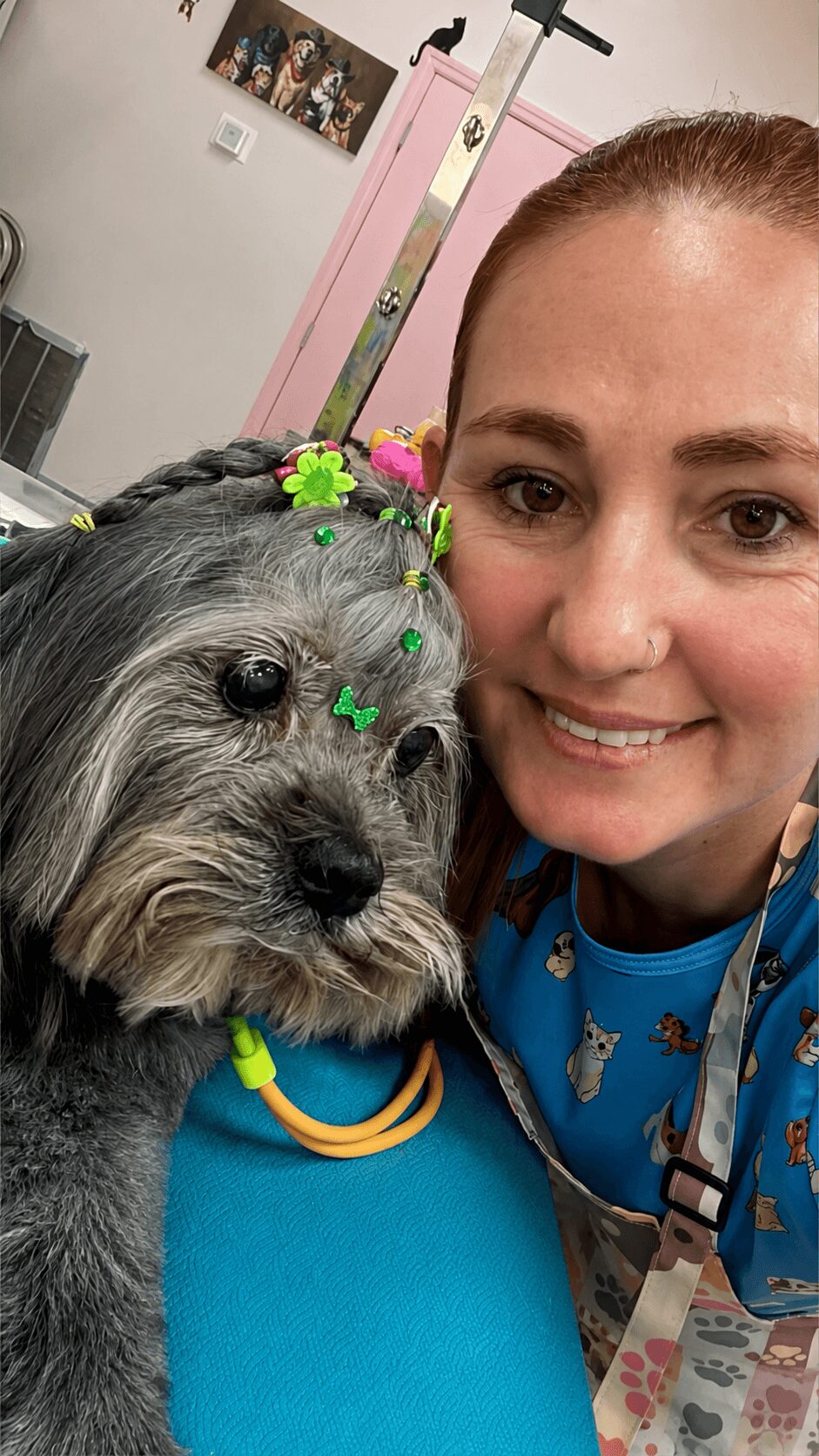 Woman with a dog decorated with colorful flowers and a yellow collar, both close to the camera.