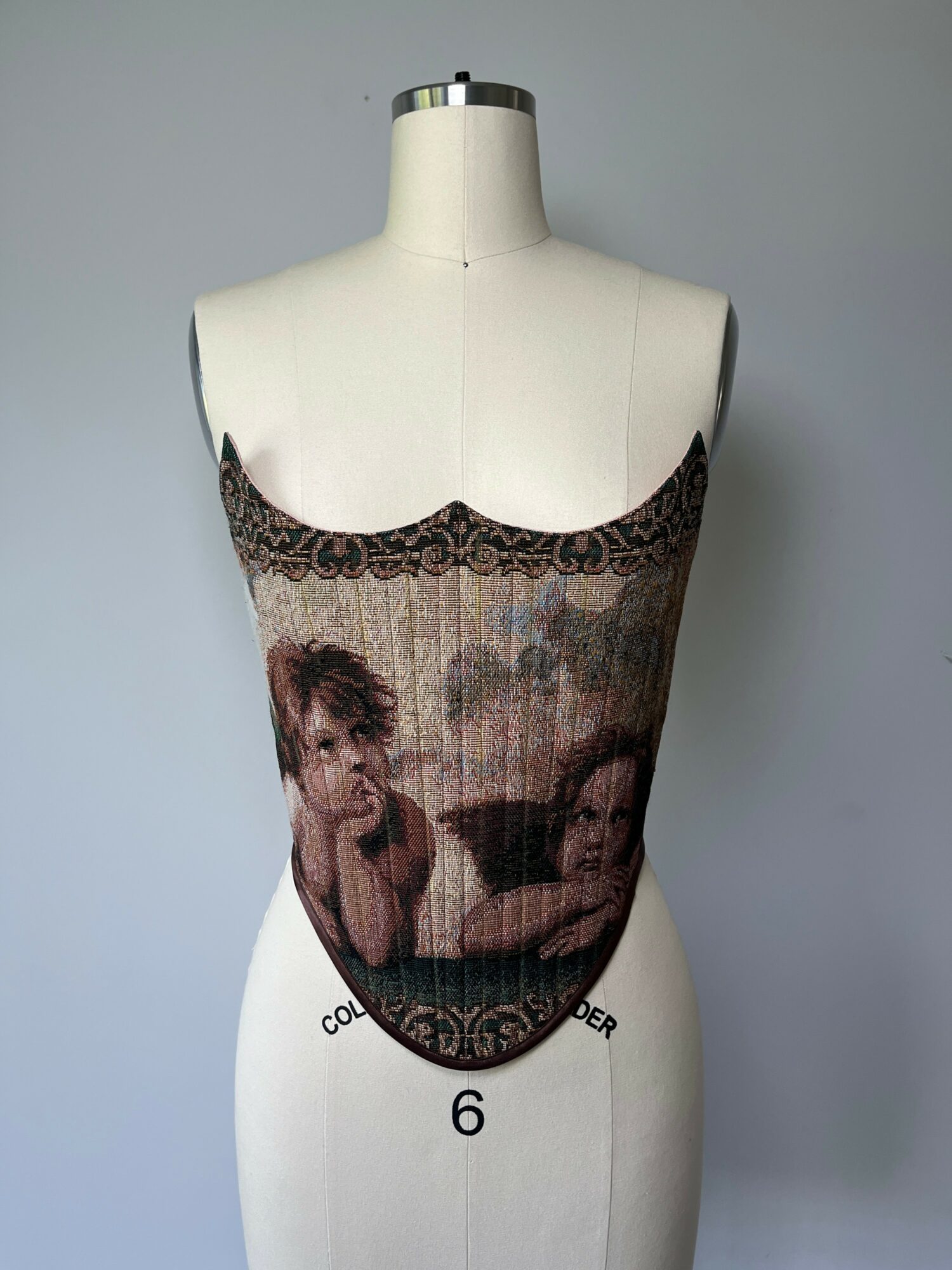Lace-trimmed top with a printed image of two women, displayed on a dress form against a plain background.