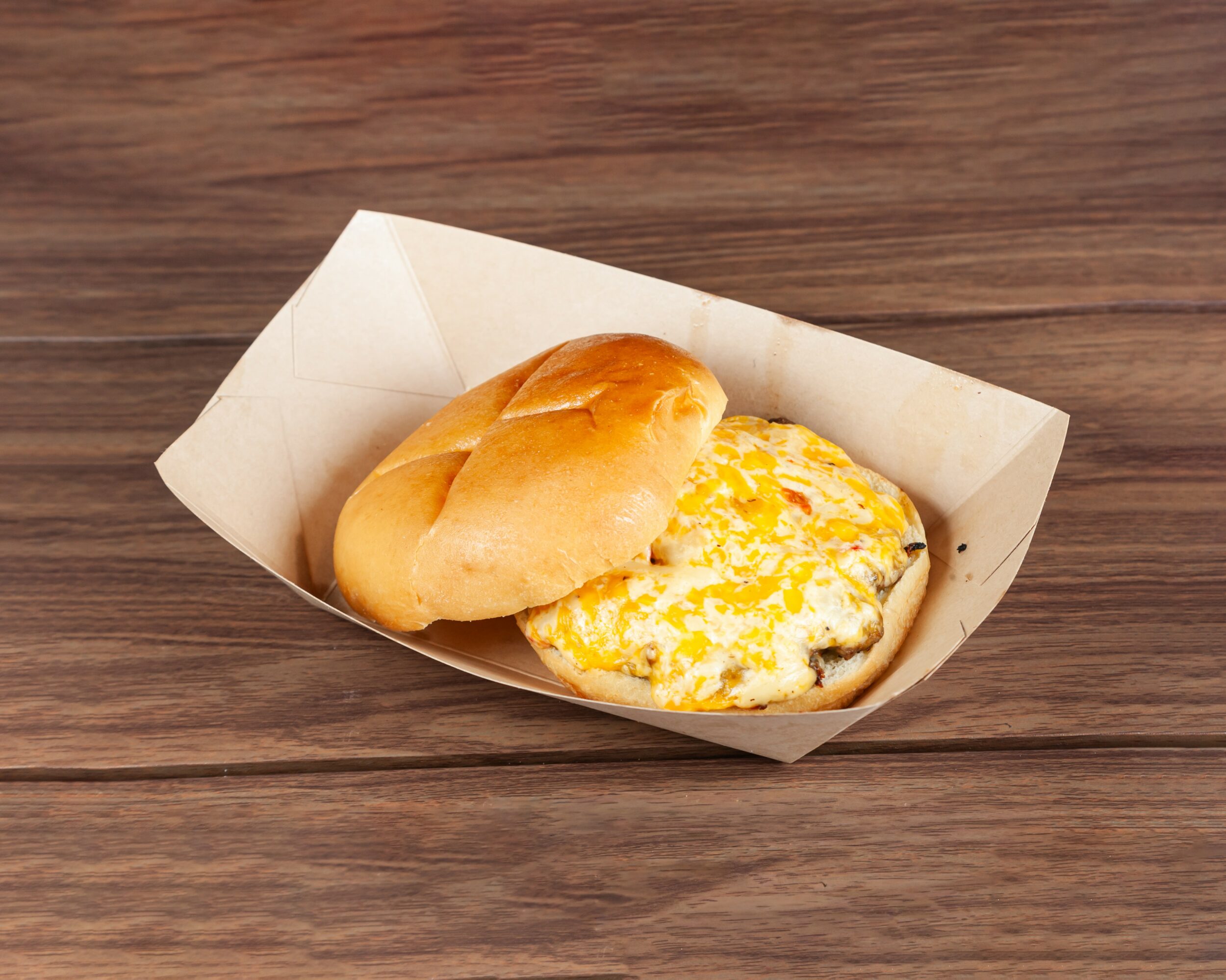 Two bread rolls, one plain and one with scrambled eggs, in a paper tray on a wooden surface.