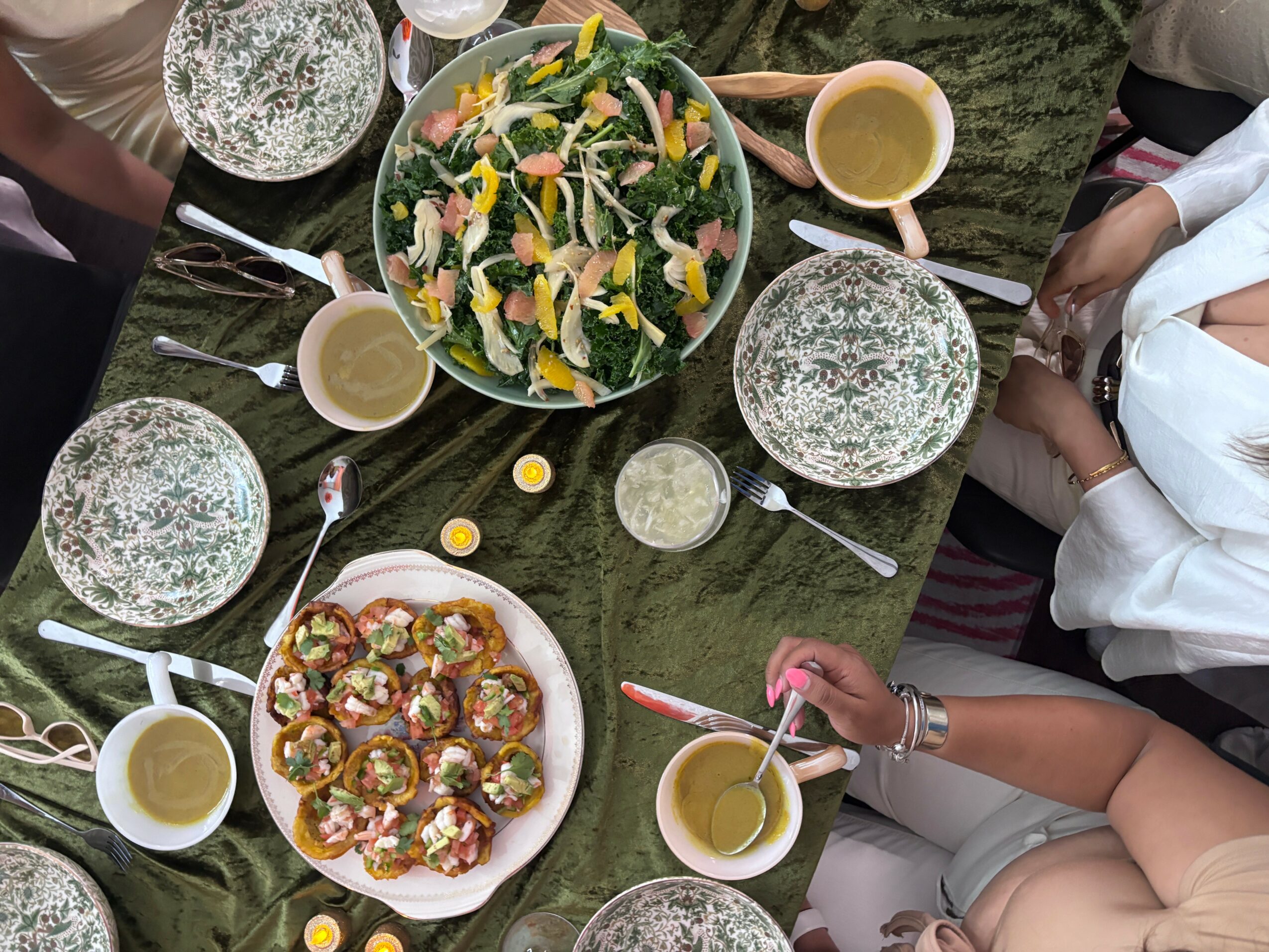 People gathered around a table with salad, appetizers, and drinks, seen from above.