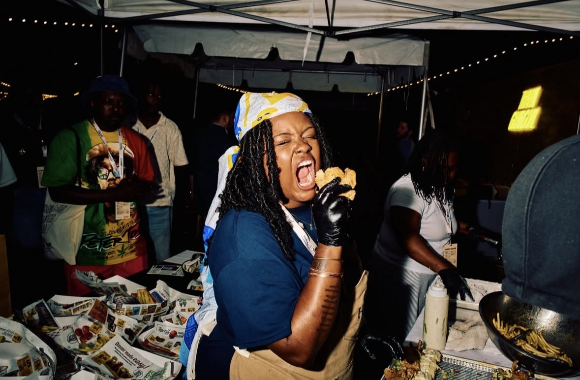 Woman singing passionately at a market stall with people around, night setting, illuminated by string lights.