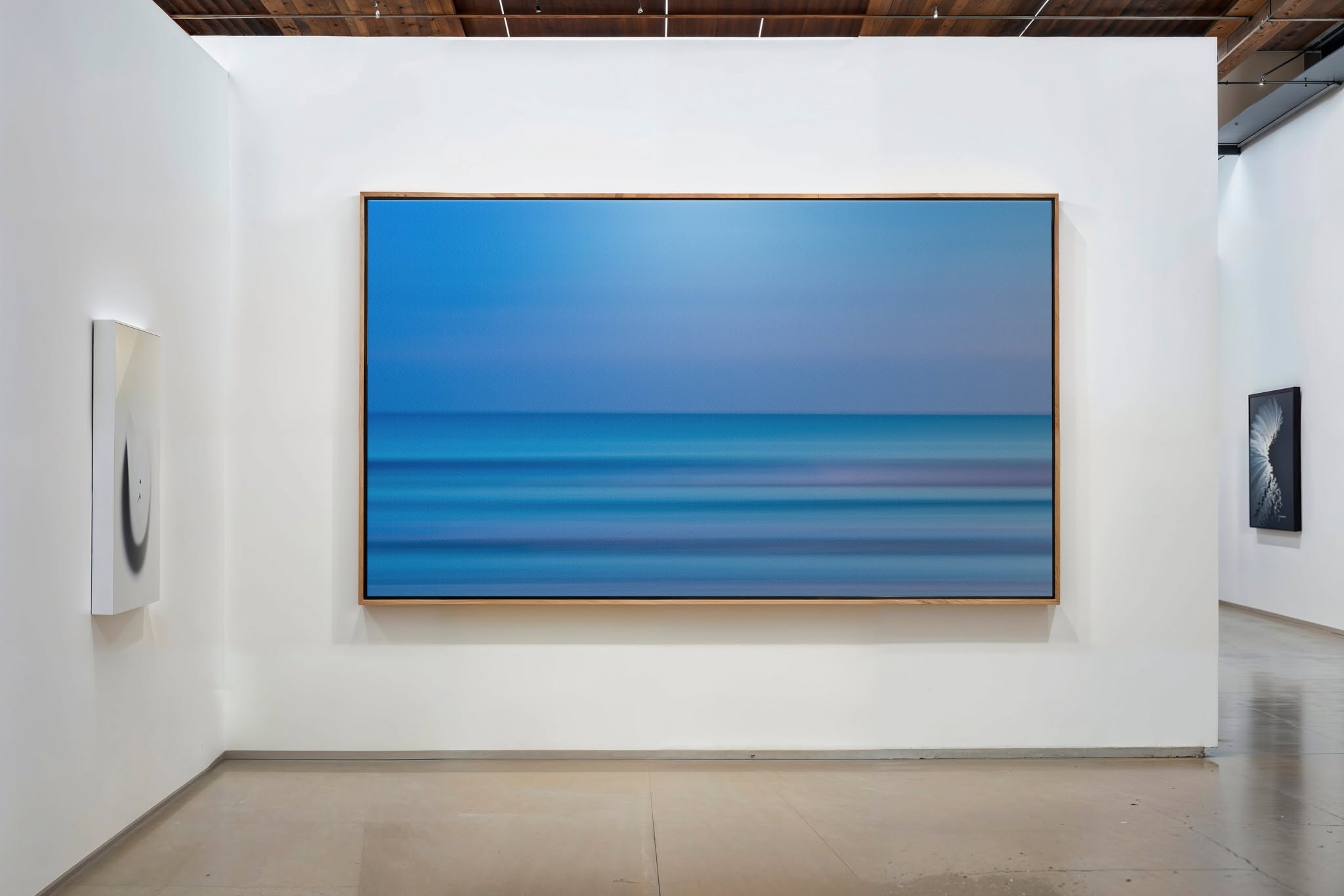Large blue abstract painting with horizontal lines on a white gallery wall.
