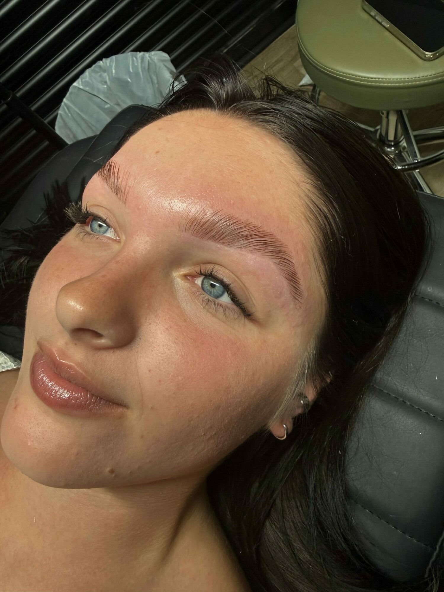 Woman with dark hair and blue eyes lying down, looking to the side, with a neutral expression.