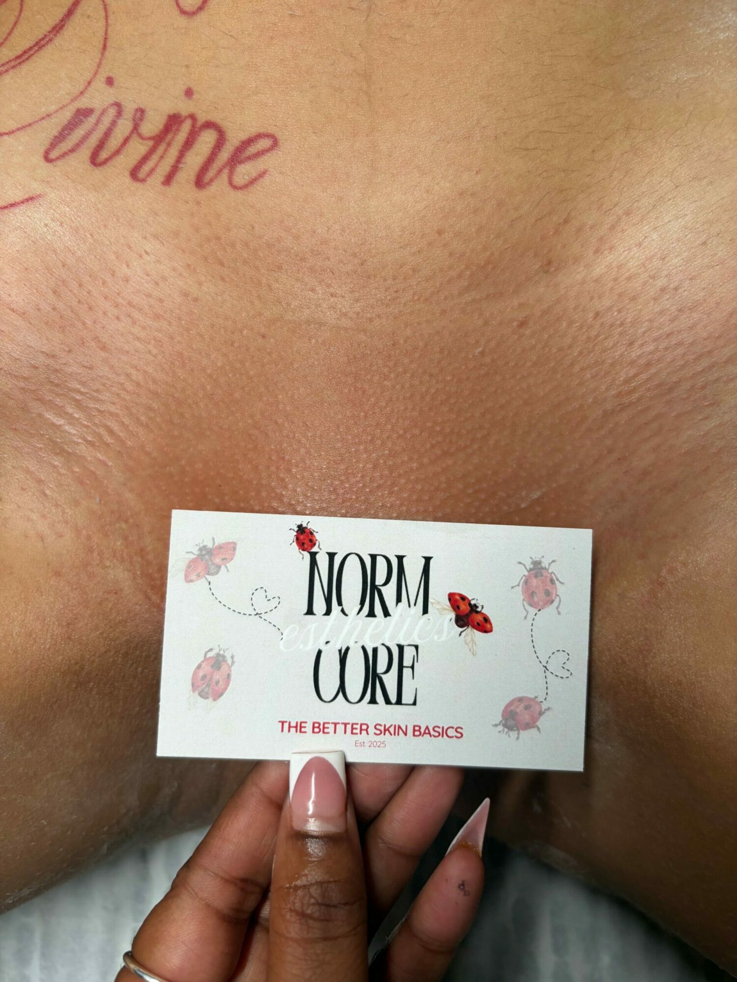 Person holding a card with floral design and text, close-up of chest area, skin tone visible.