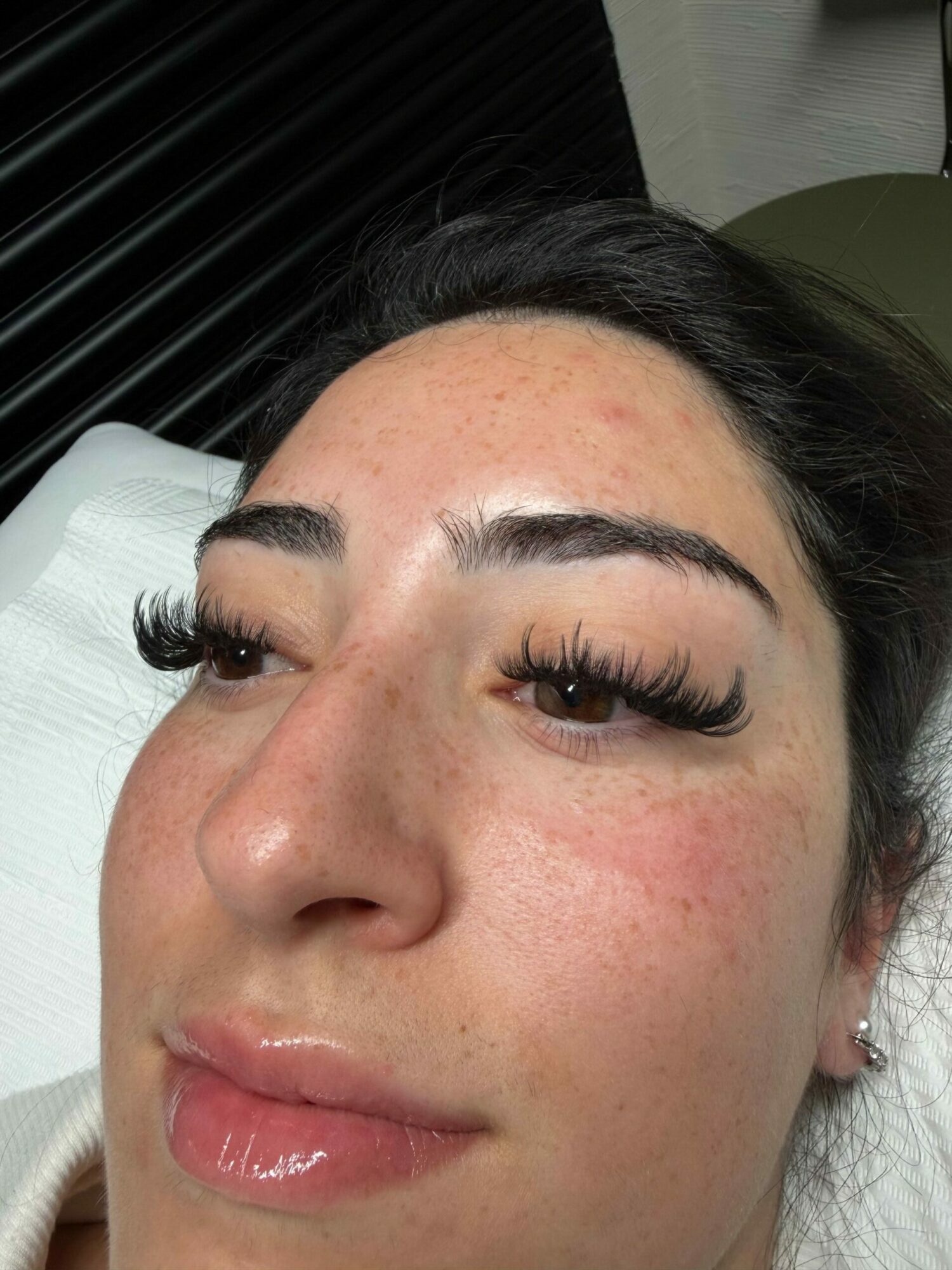 Close-up of a woman's face with makeup, lying down, showing her forehead, eyes, nose, and lips.