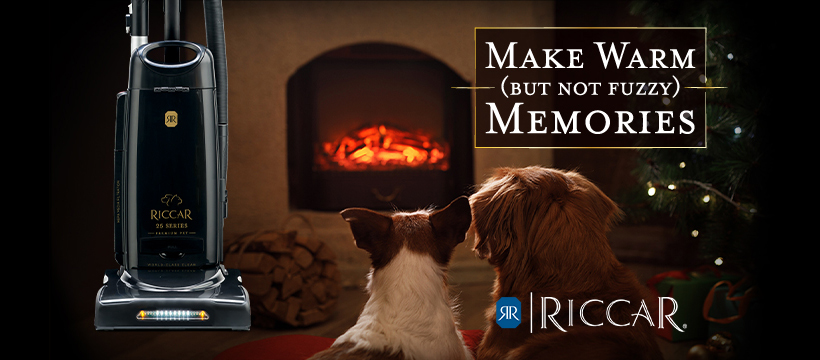 Two dogs sit in front of a fireplace with a banner reading 'Make Warm Memories' and a Riccar vacuum cleaner nearby.