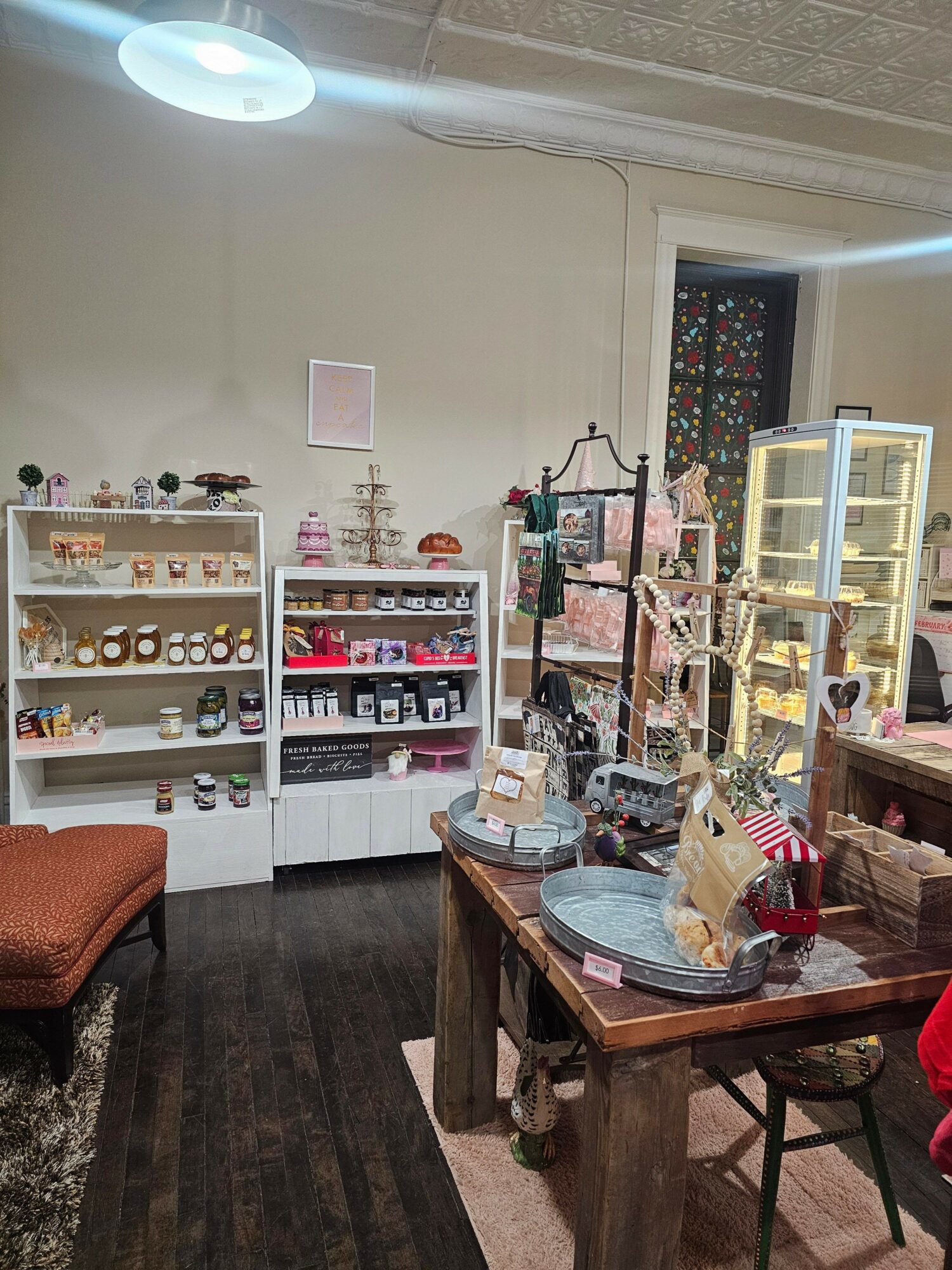 Room with shelves, table, and various decorative items, viewed from the side with a window in the background.