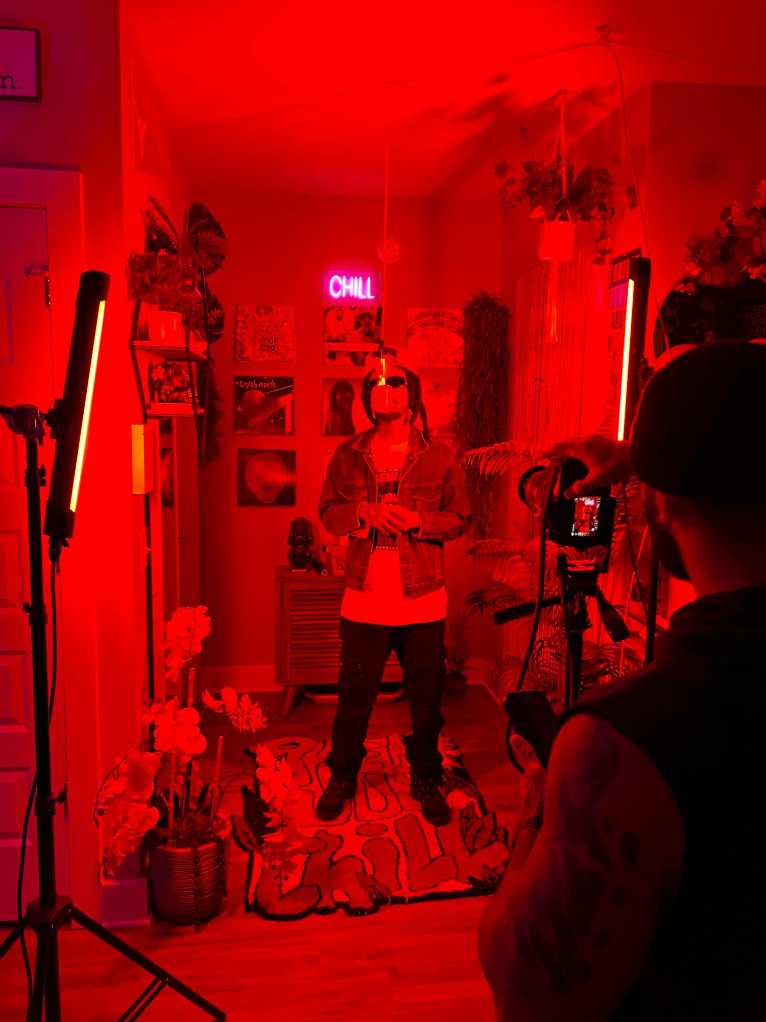 People gather in a room illuminated by red light, with a neon sign and various decorations on the walls.