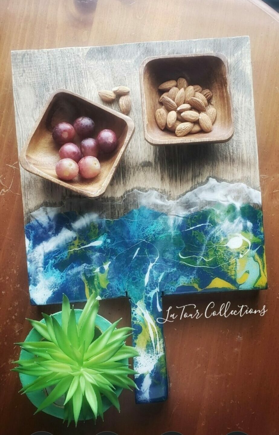 Two wooden bowls with pills and tablets on a wooden surface, a green plant, and a colorful card with water and land illustration.