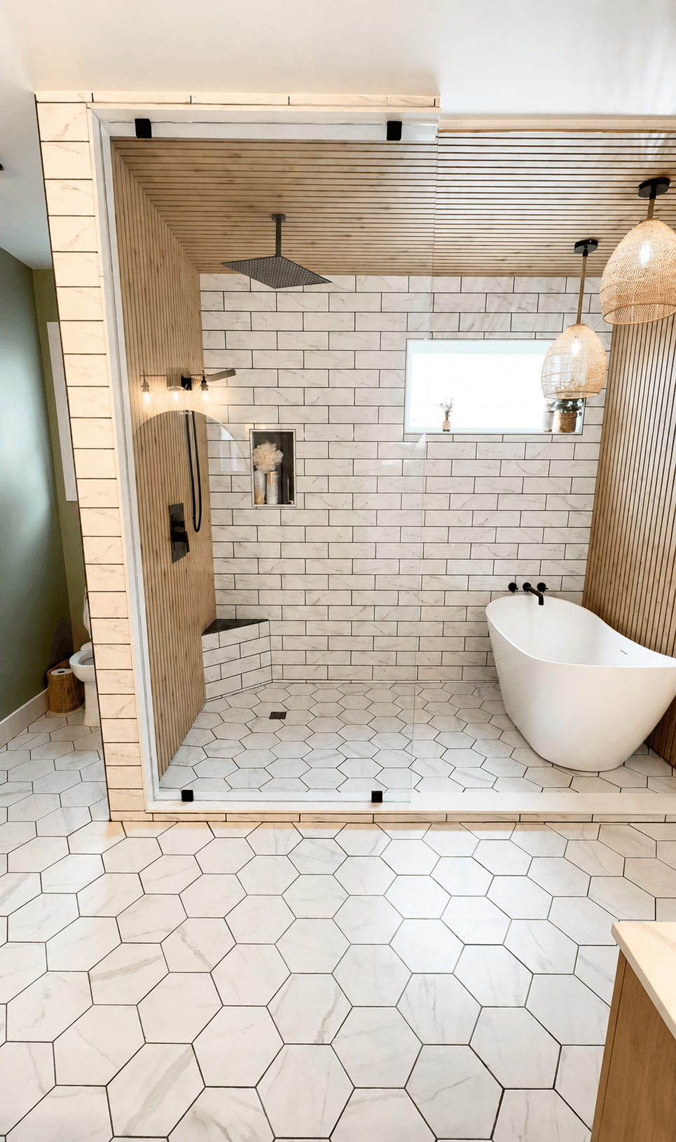 Bathroom with walk-in shower, white brick wall, hanging lights, and a freestanding bathtub, with hexagonal floor tiles.