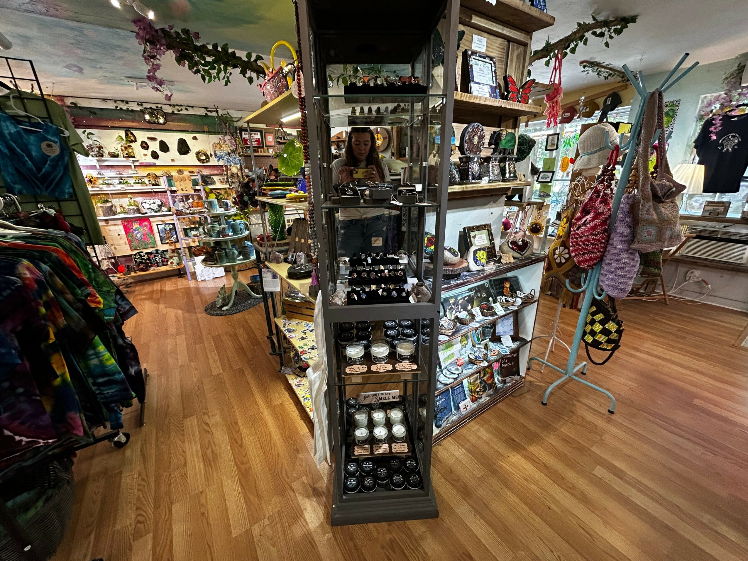 View of a store interior with shelves of various items, clothing, and accessories, and a wooden floor.