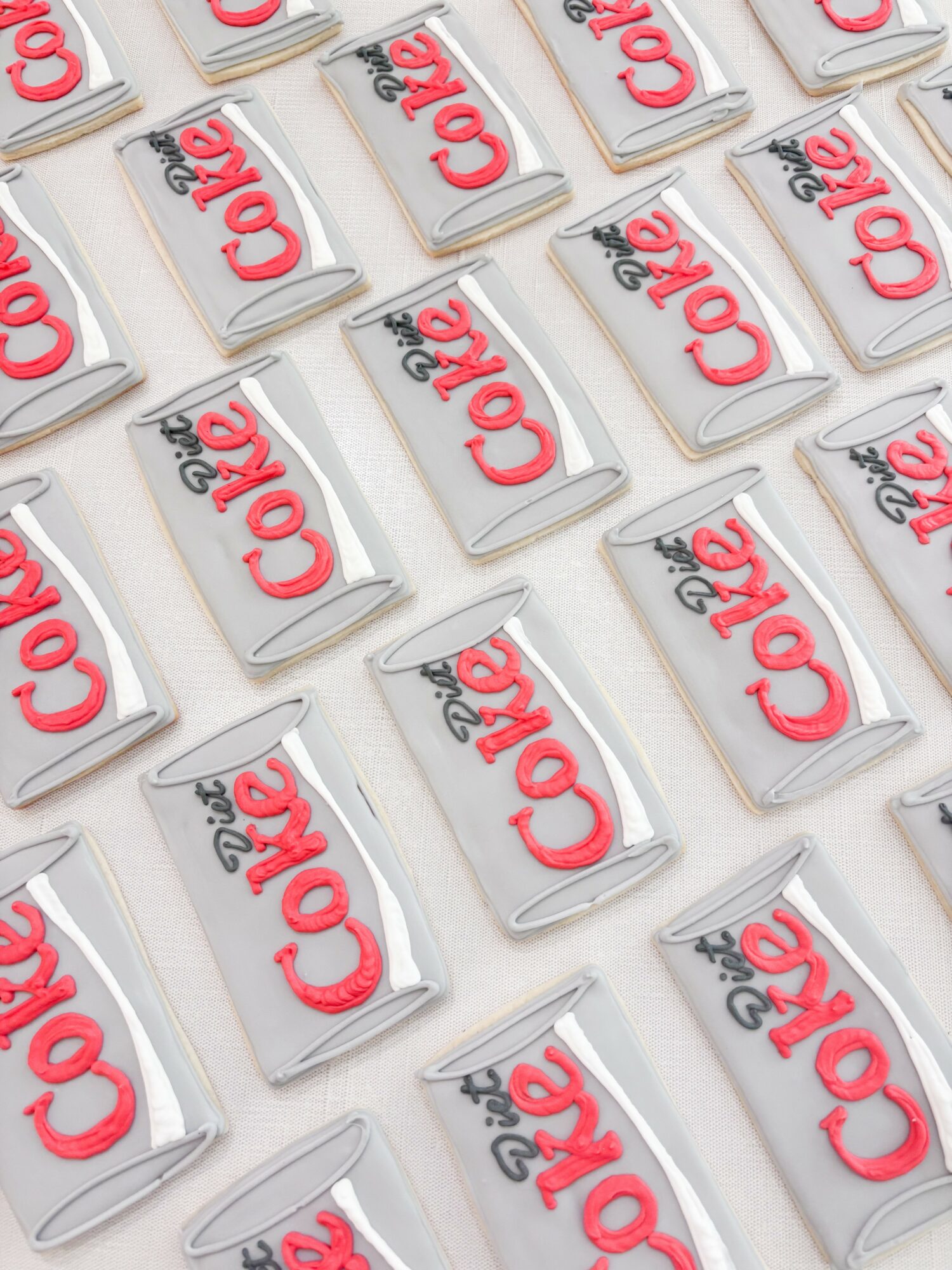 Multiple cans of Coca-Cola arranged in a pattern, with red logo on silver cans, viewed from above.